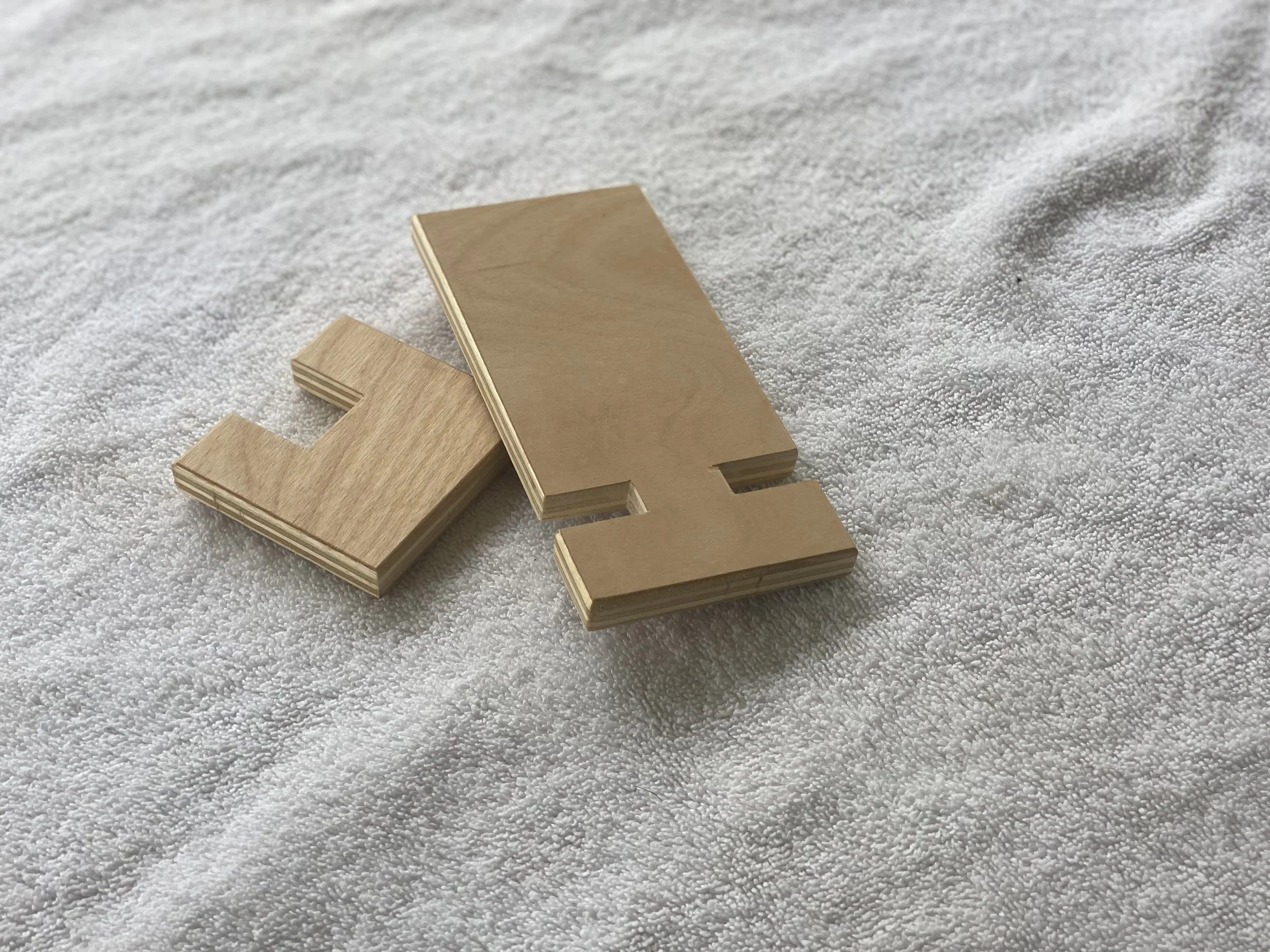 A wooden block with a cut-out in the shape of a letter or number, placed on a white textured surface.