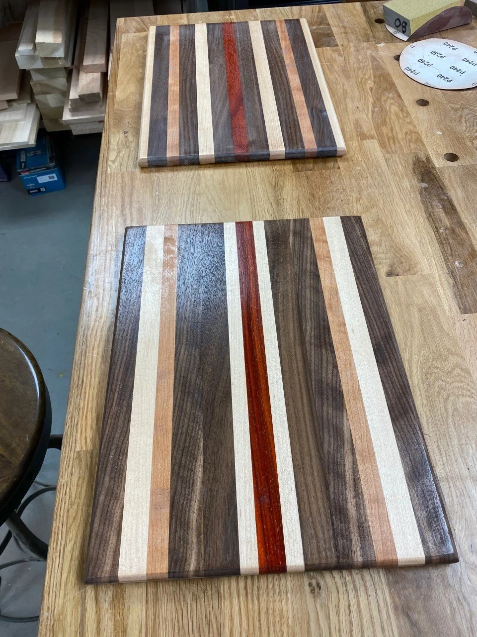 Two wooden cutting boards with striped wood patterns placed on a workbench.