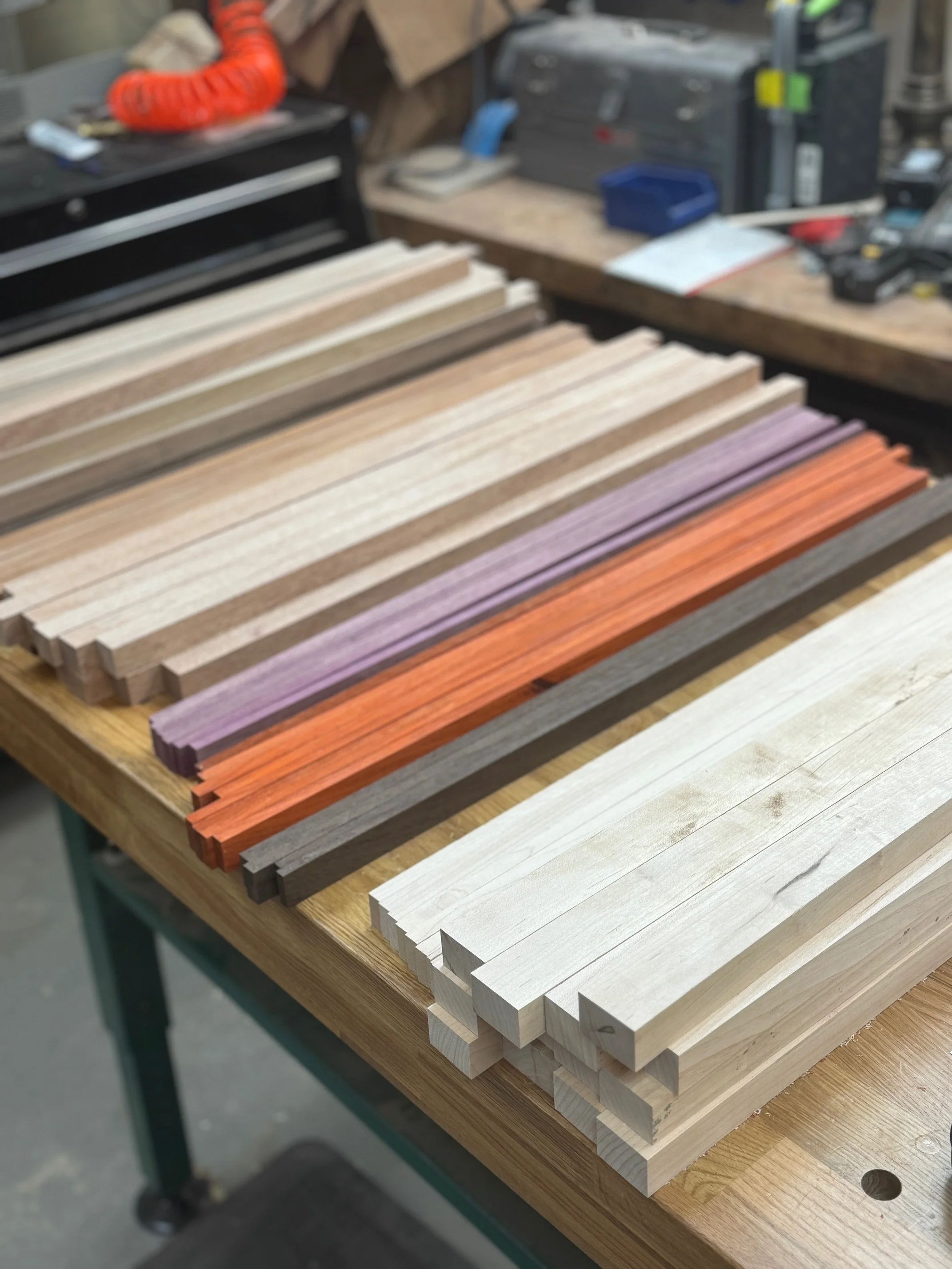Wooden slats in various colors neatly arranged on a workbench in a workshop.