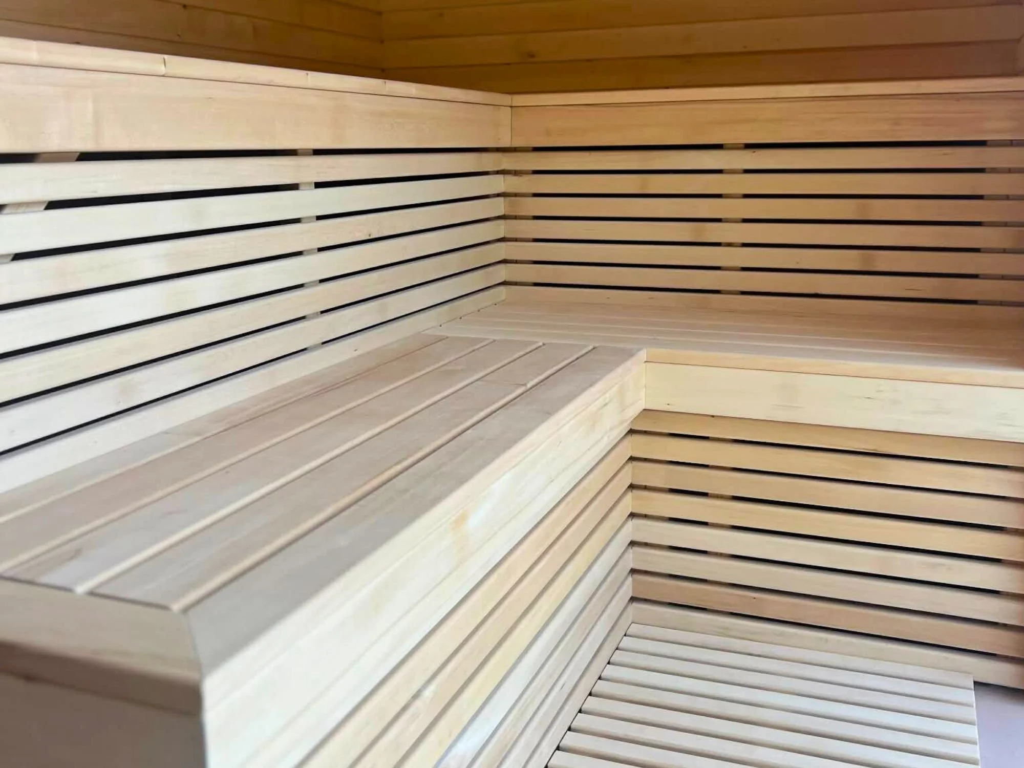 Interior of a Nordbadstu timber sauna with light aspen benches.