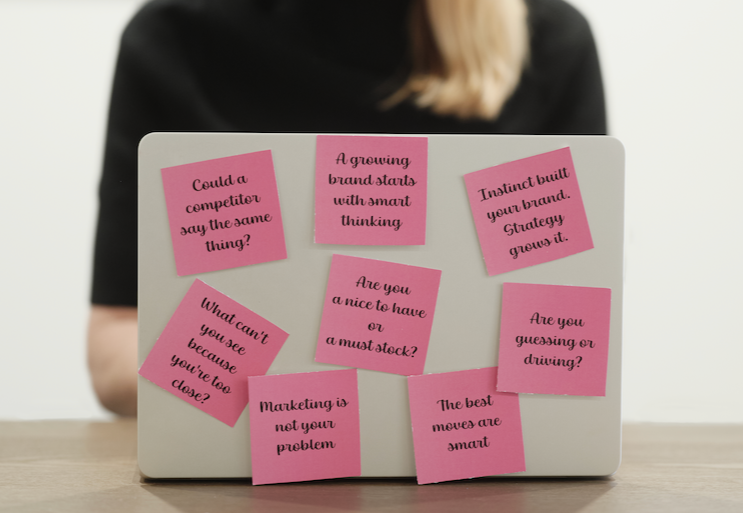 A hand holding a pink brochure with a black torn strip across the center that reads 'Your path to smarter marketing starts here.'