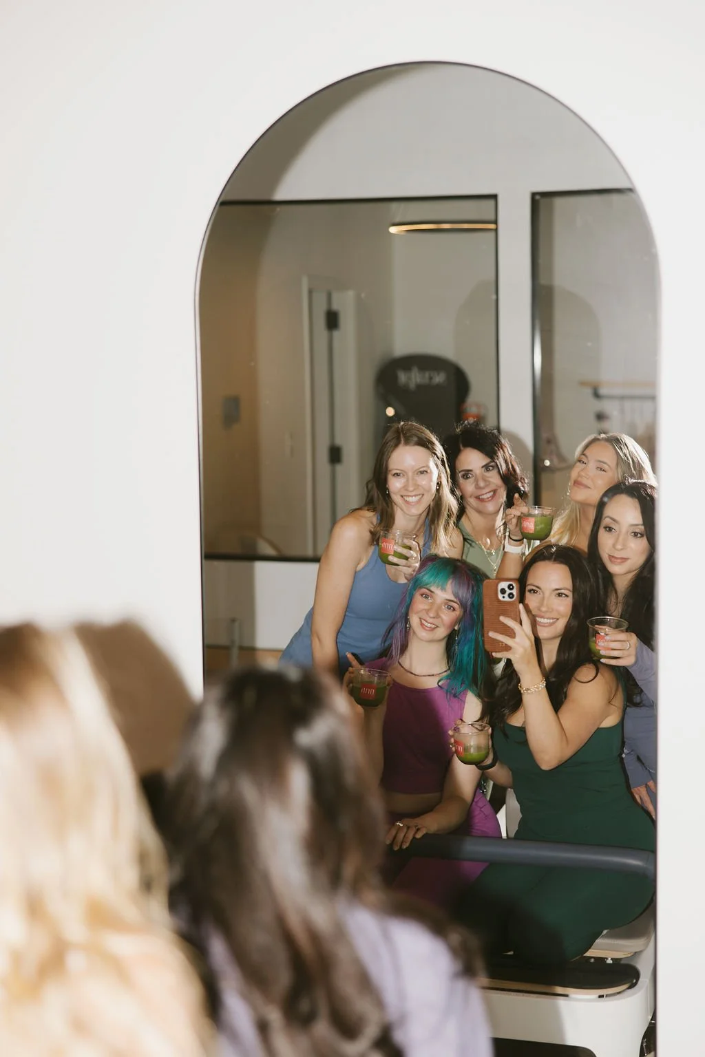 Group of women taking a selfie in front of a mirror during a celebration or party.
