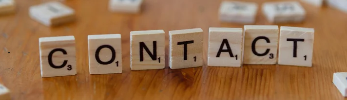 Scrabble tiles spelling out the word 'CONTACT' on a wooden surface.