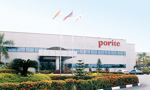 Exterior of a building with a sign that says 'porite', surrounded by palm trees and a parking lot with cars.