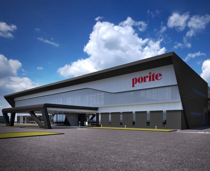 A modern commercial building with the word 'porite' on it, featuring a unique angular design and a large overhang near the entrance, against a backdrop of a blue sky with clouds.