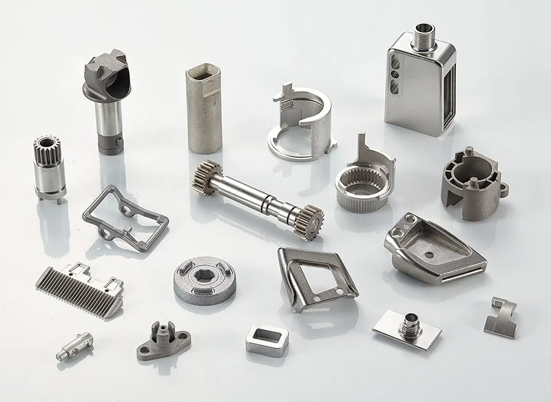 Collection of various metal machined parts and components on a white surface.