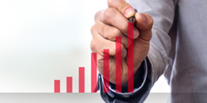 Business person drawing an upward trending red bar graph on a transparent surface.