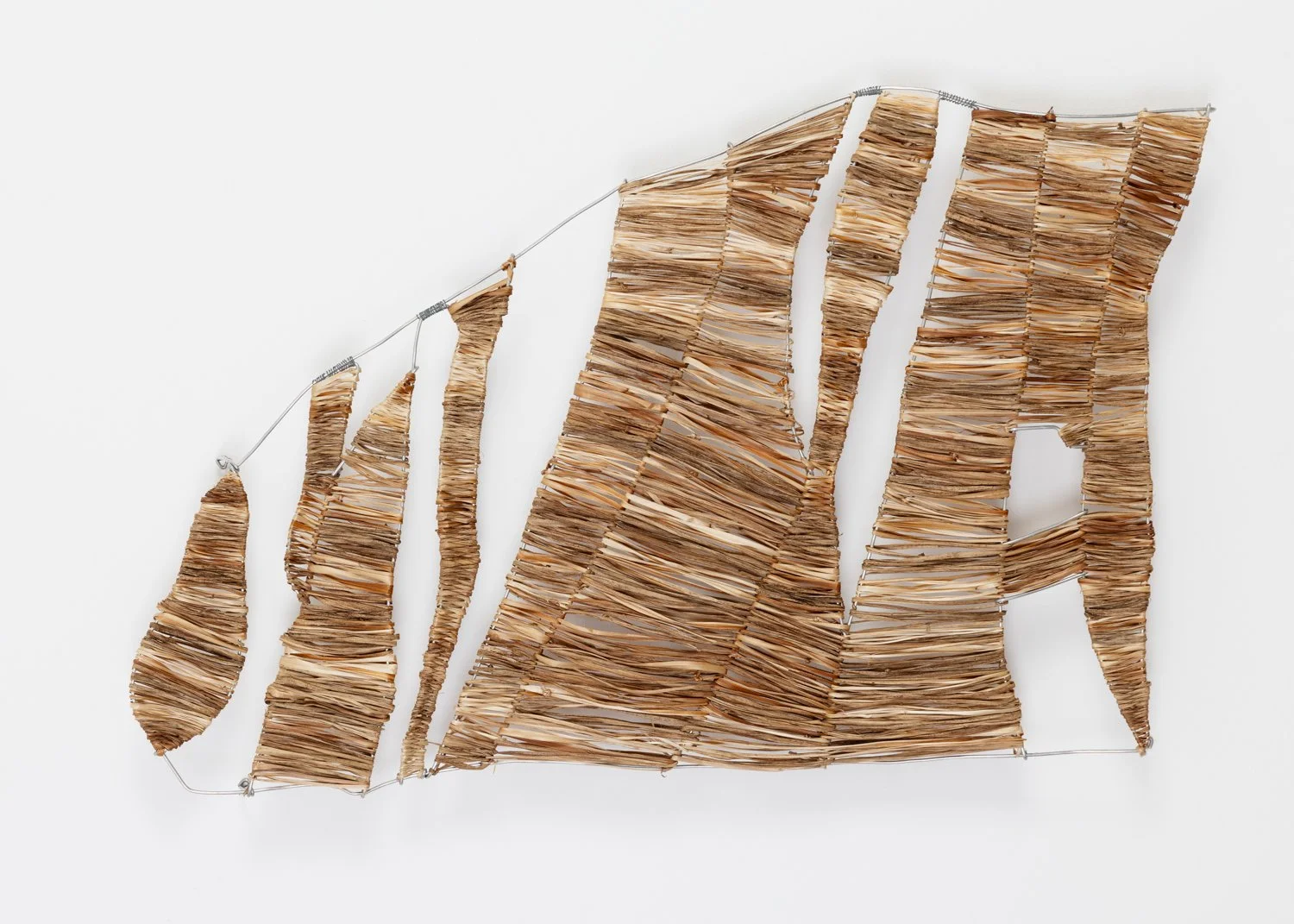 Fibre sculpture made with  a wire frame filled with dried watsaonia fibres arranged in the shape of coastal rock formations with an upward trend, mounted on a white background.