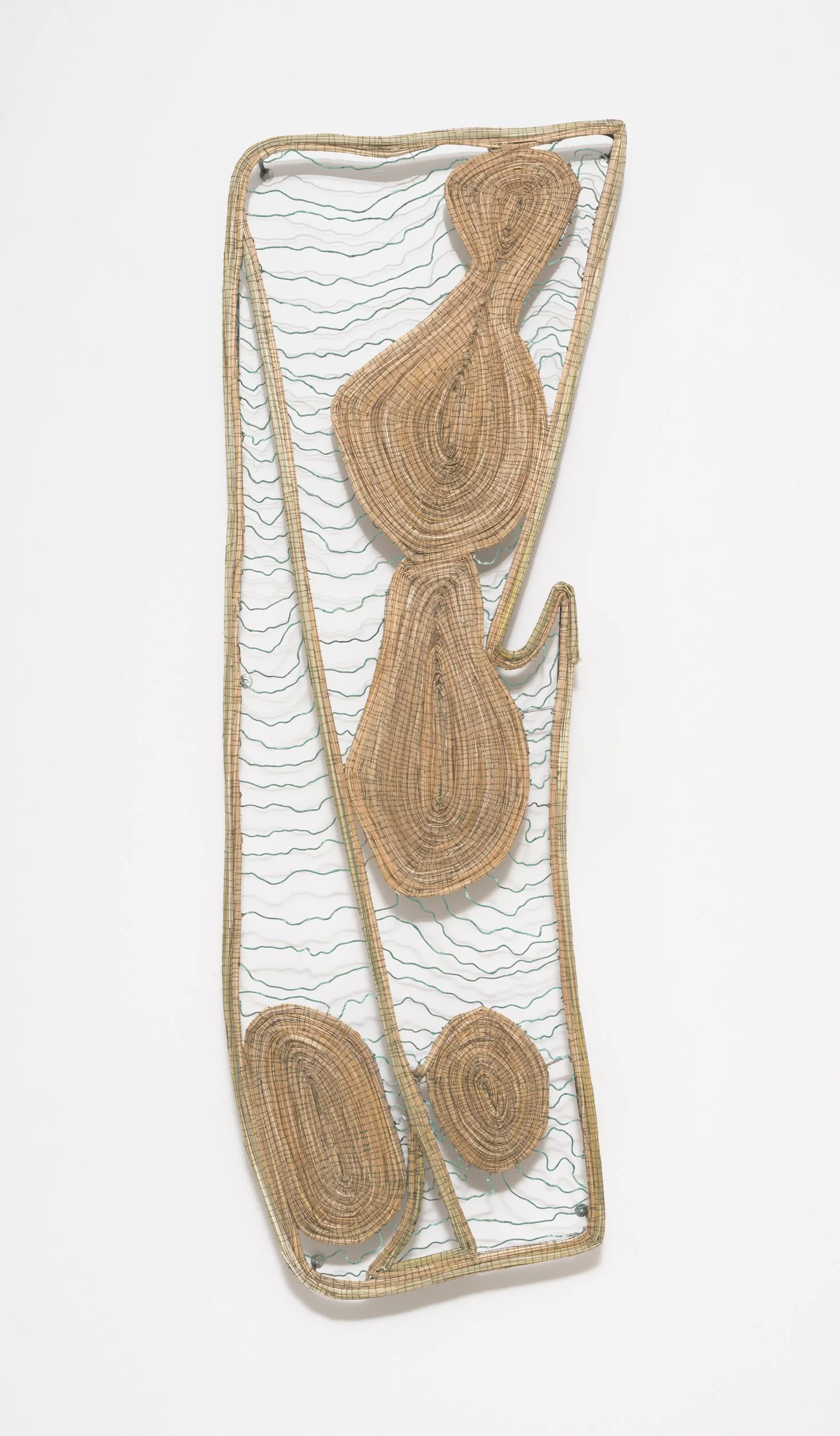 Art installation made of woven wood and wire, resembling a stylized plant or botanical form, mounted on a white wall.