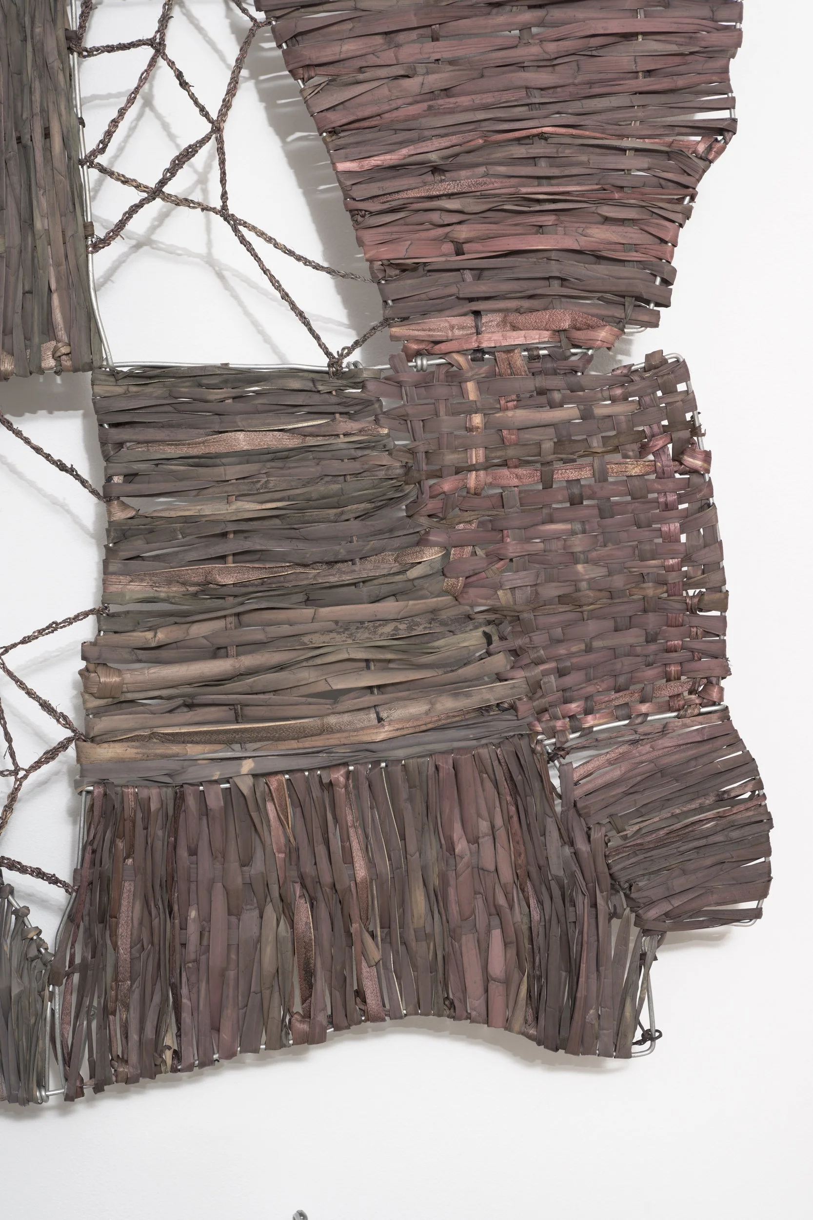 Close-up of woven leather or rattan panels with rope details, arranged to form a decorative wall piece.