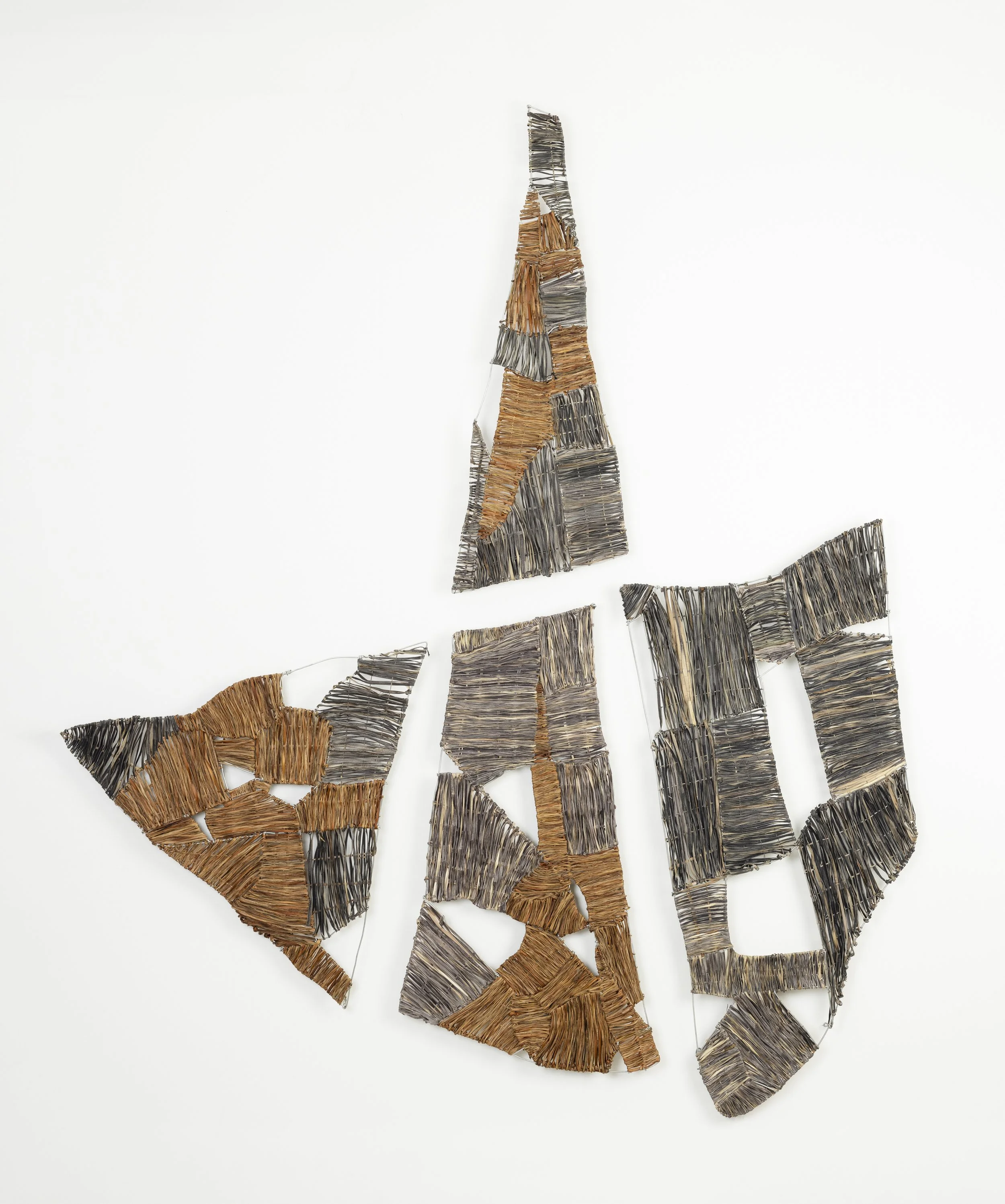 Mixed media artwork resembling a rock formation made from interwoven fibre and metal pieces mounted on a white wall.