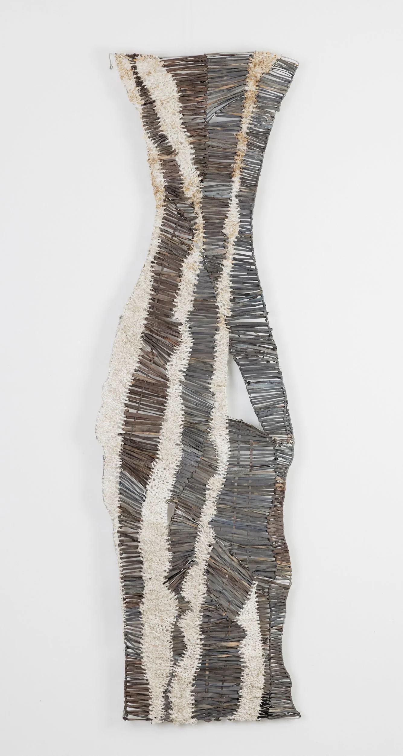 Fibre sculpture made of vwoven with grey dyed fibre material with cream-colored textured rope strings creating a wavy, elongated shape.