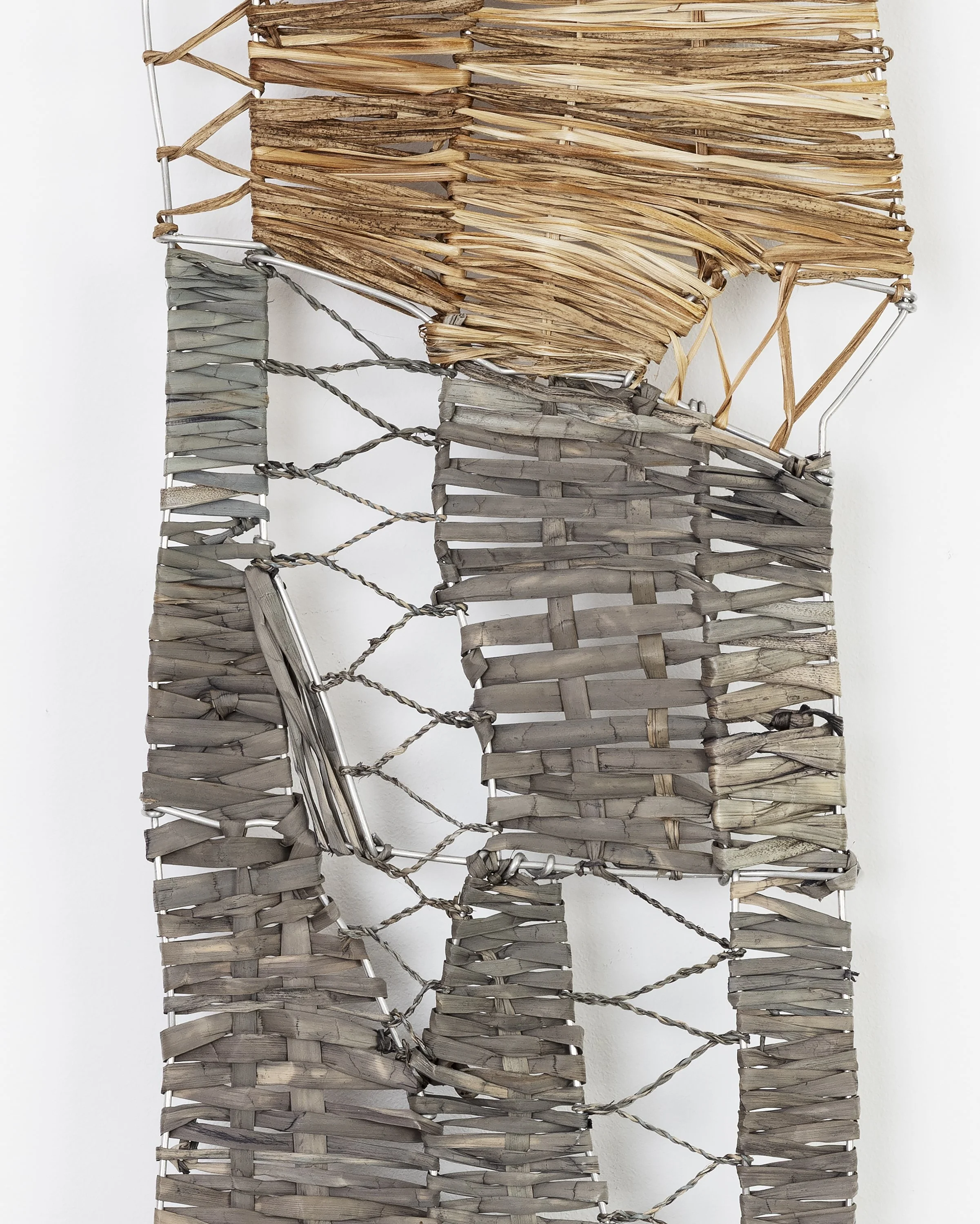 Close-up of woven wicker and metal wire structures with some dried plant material woven in.