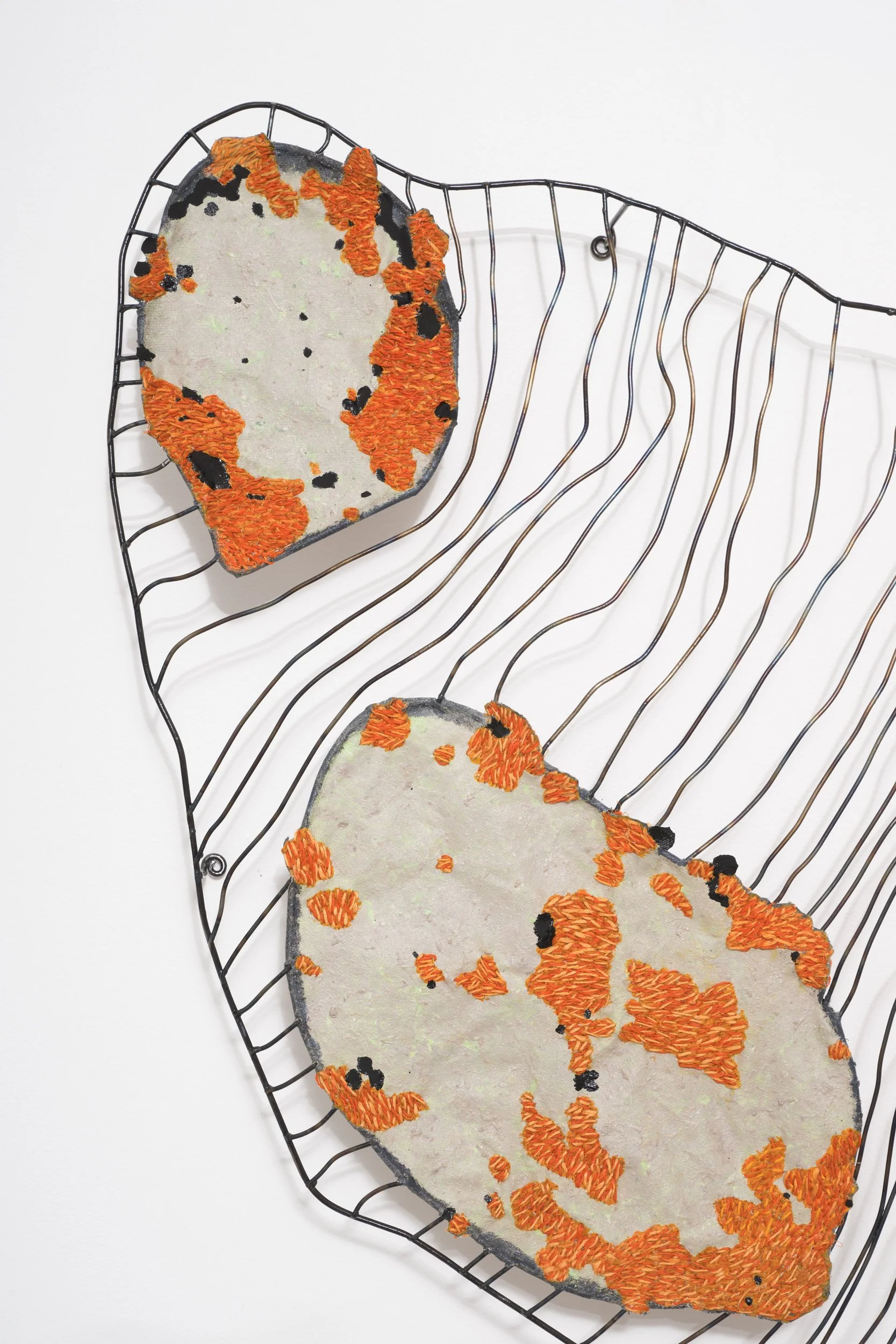 An art piece featuring embroidered patches of a dog, mounted on wire frames.