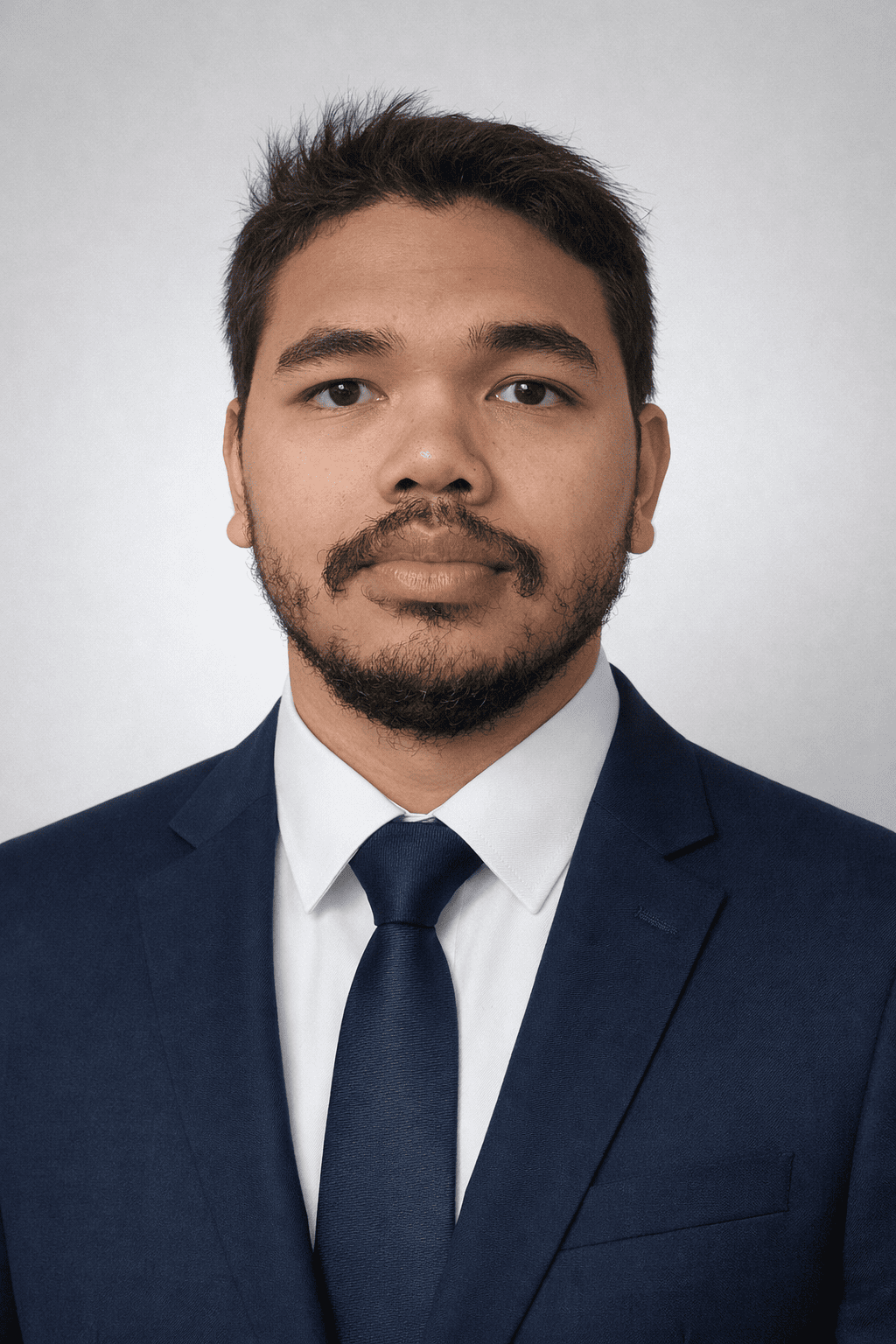 Razafindraibe Jimmy Chandro  Etudiant BTS NDRC  (Neogciation et digitilisation de la relation client)
Portrait d'un homme portant un costume bleu, chemise blanche et cravate, avec une barbe et moustache, regardant vers l'avant.