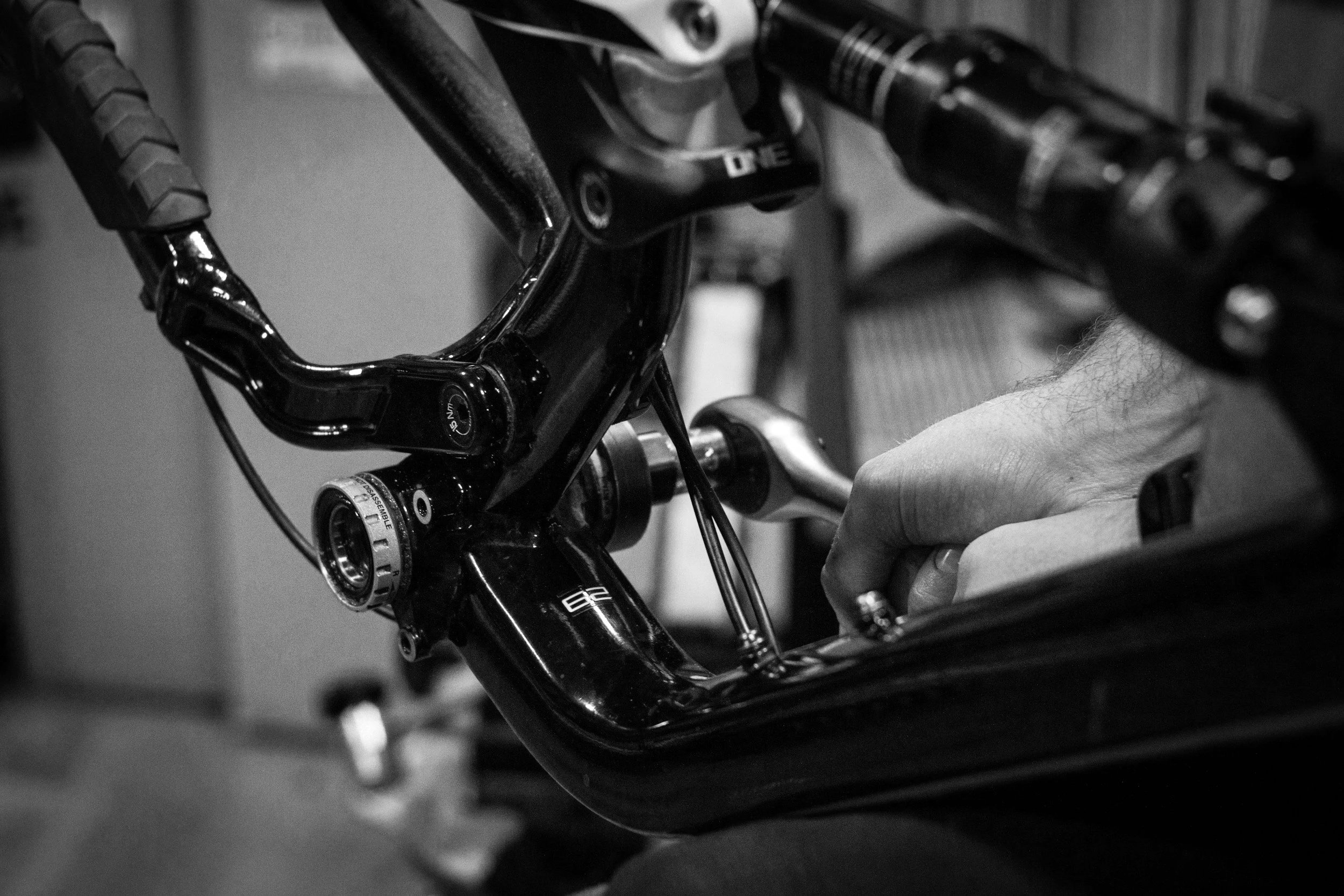 A black and white photo of a person adjusting the handlebars of a bicycle.