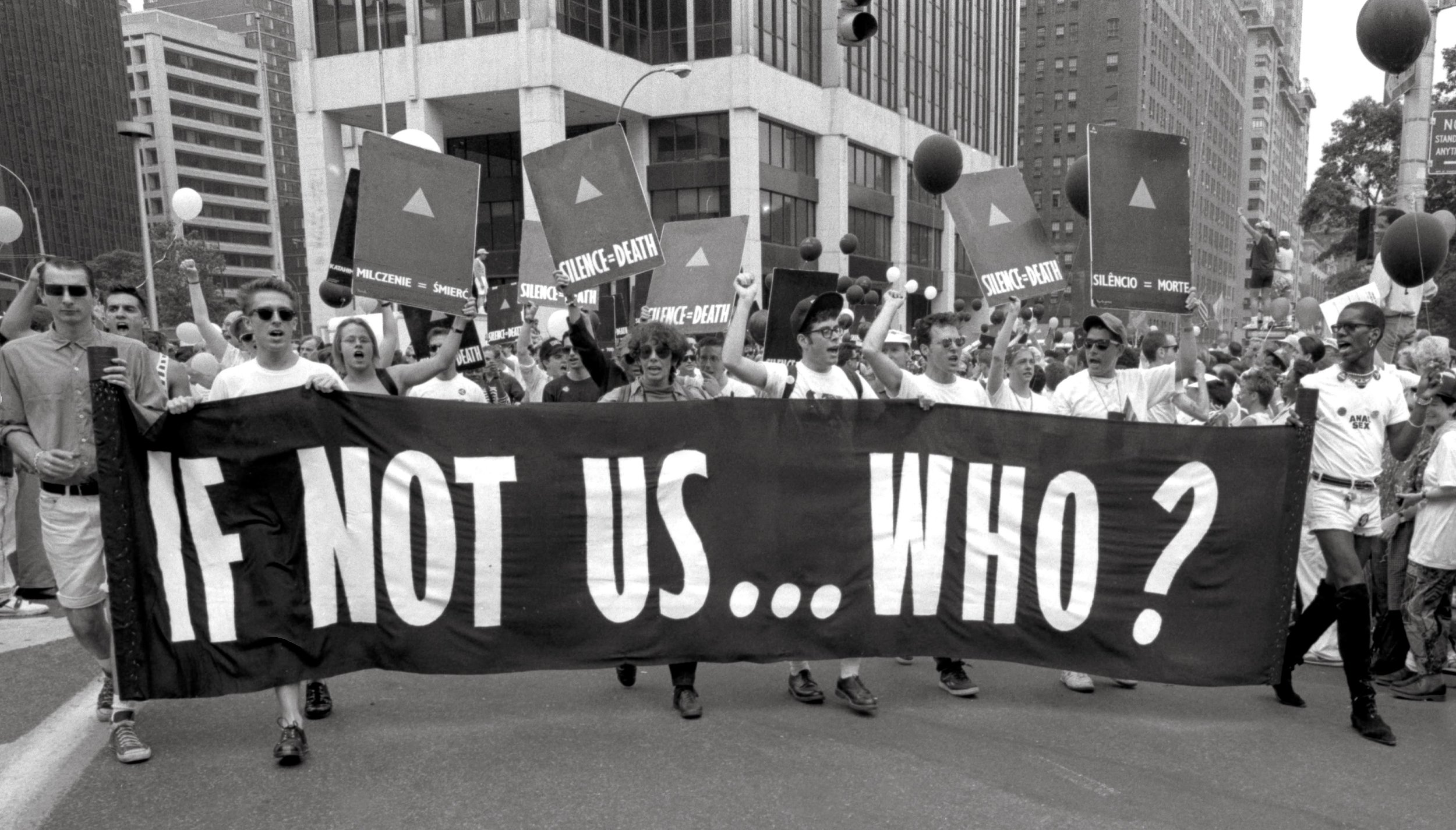 Black and White Image of people marching for LGBT rights with a banner that says IF NOT US...WHO? and signs that say SILENCE = DEATH