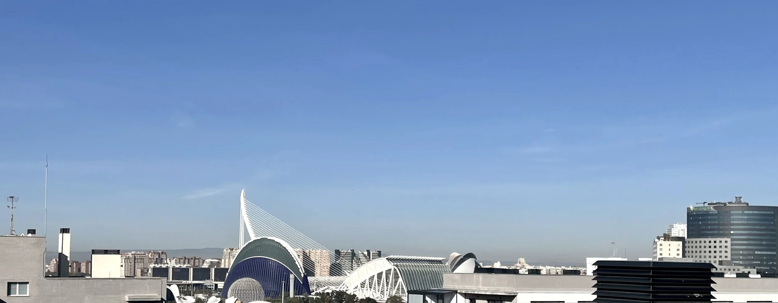 Vista panorámica del skyline de una ciudad con edificios modernos, incluyendo estructuras con diseños innovadores y un cielo despejado.