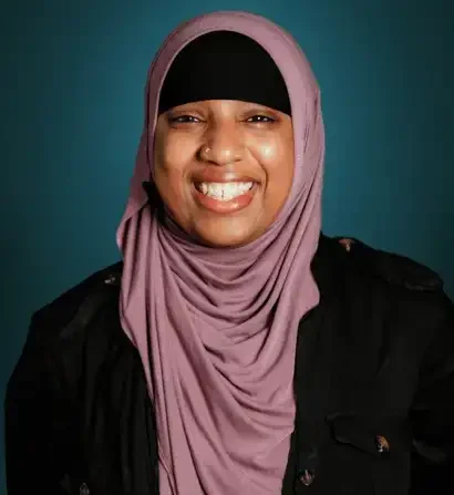 Smiling woman wearing a mauve Hajib and black top