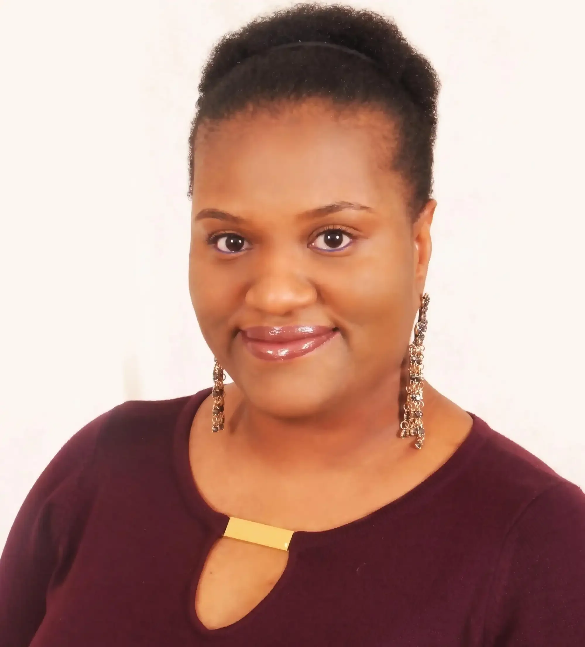 Smiling woman with long drooping earrings and mauve top facing the camera