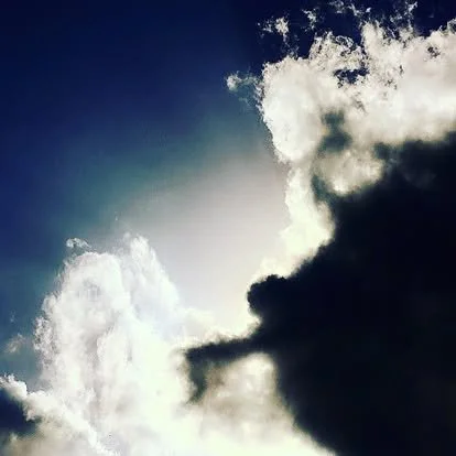 Cloudy sky with dark and bright clouds and sunlight streaming through