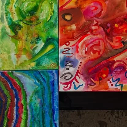 A collage of three watercolor paintings, featuring a smiling green face with abstract features, a vibrant swirl of pink and red with expressive strokes, and a rainbow with colorful bands on a textured blue background.