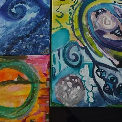 Close-up image of four abstract paintings featuring swirling patterns, vibrant colors, and various shapes displayed on a wall.