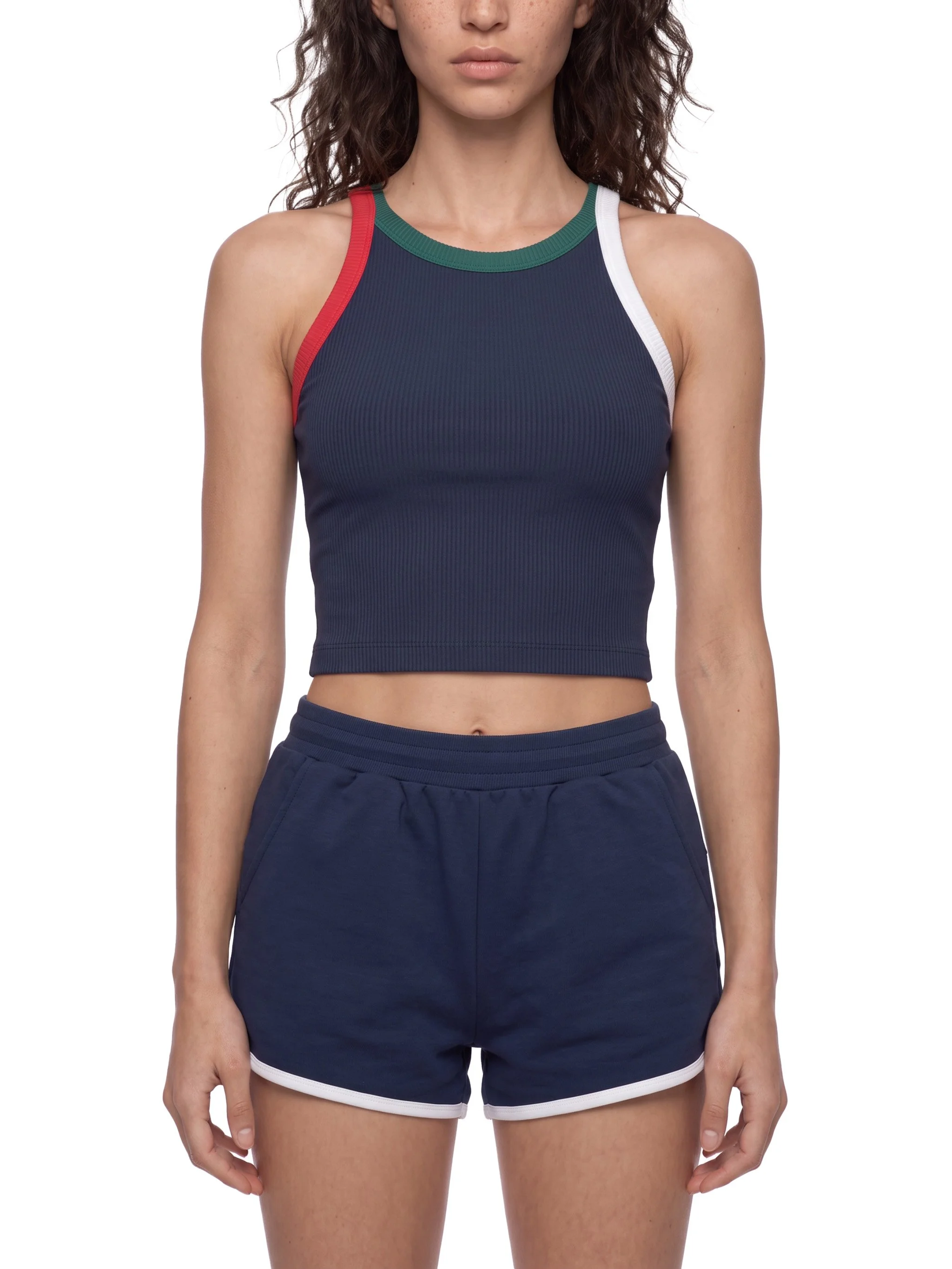 A woman wearing a navy blue sports crop top with colored trim and navy blue athletic shorts.