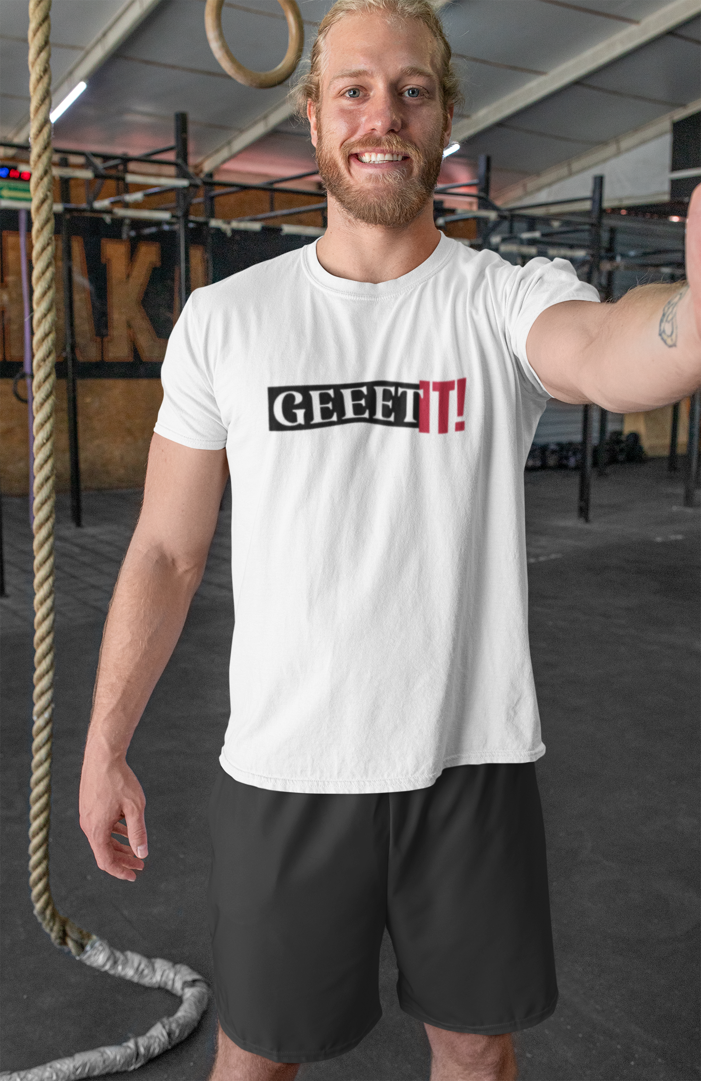 Man wearing a white Geeet IT! training shirt and black shorts in a gym