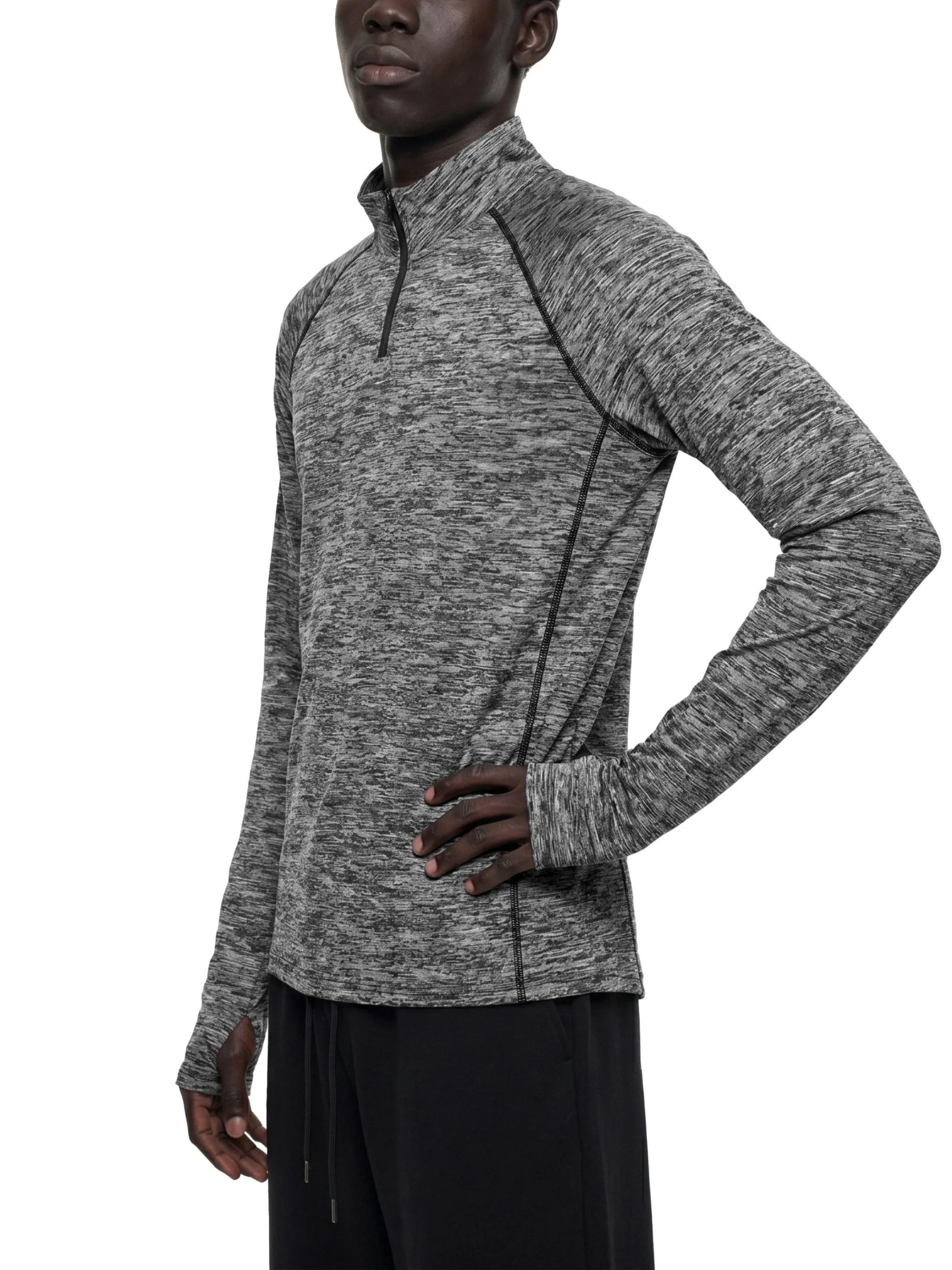 Close-up of a person wearing a gray and black athletic jacket with a high collar and black pants, standing with one hand on their hip.