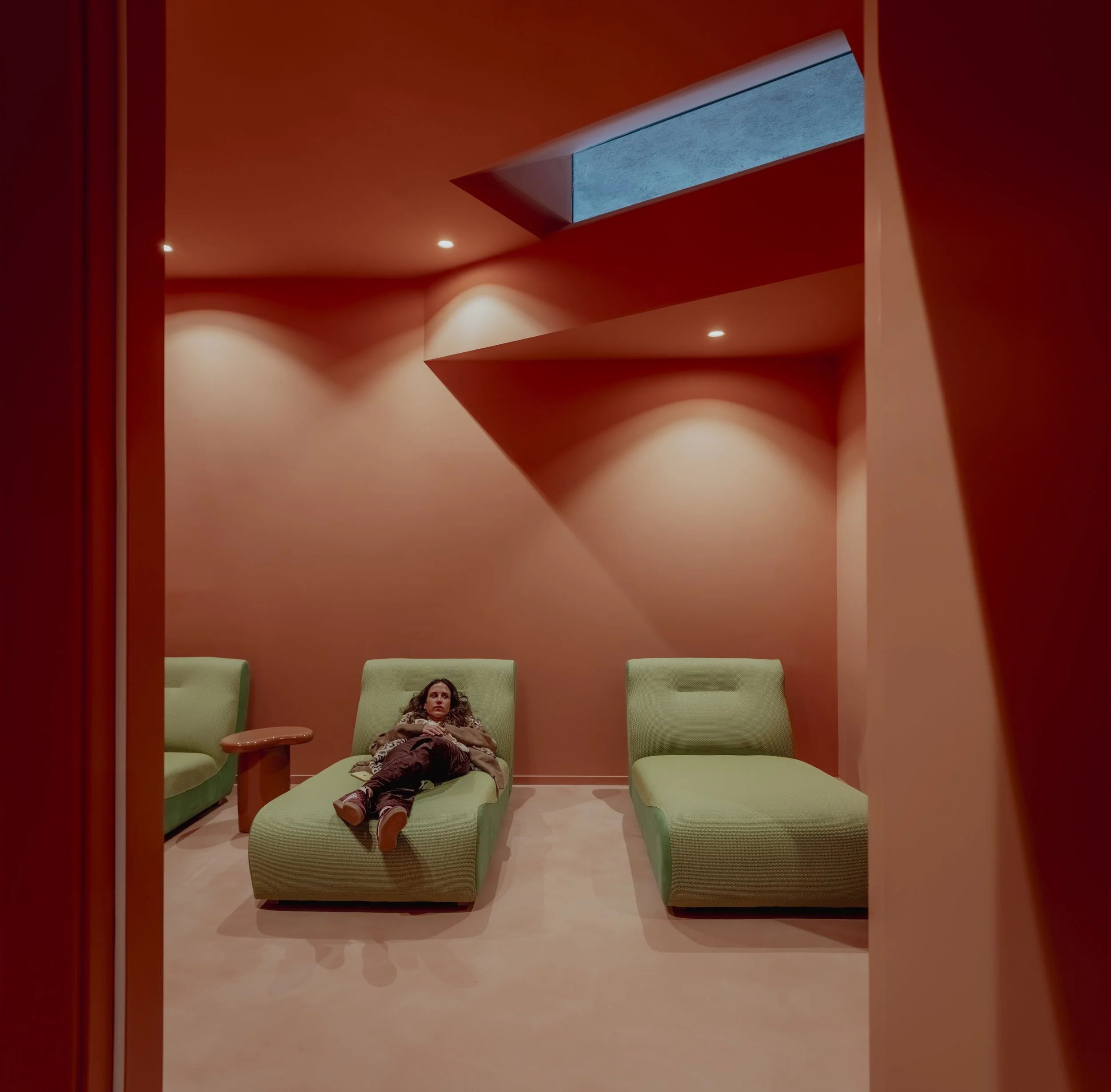 Zona de relajación con sillones verdes en sala de luz cálida