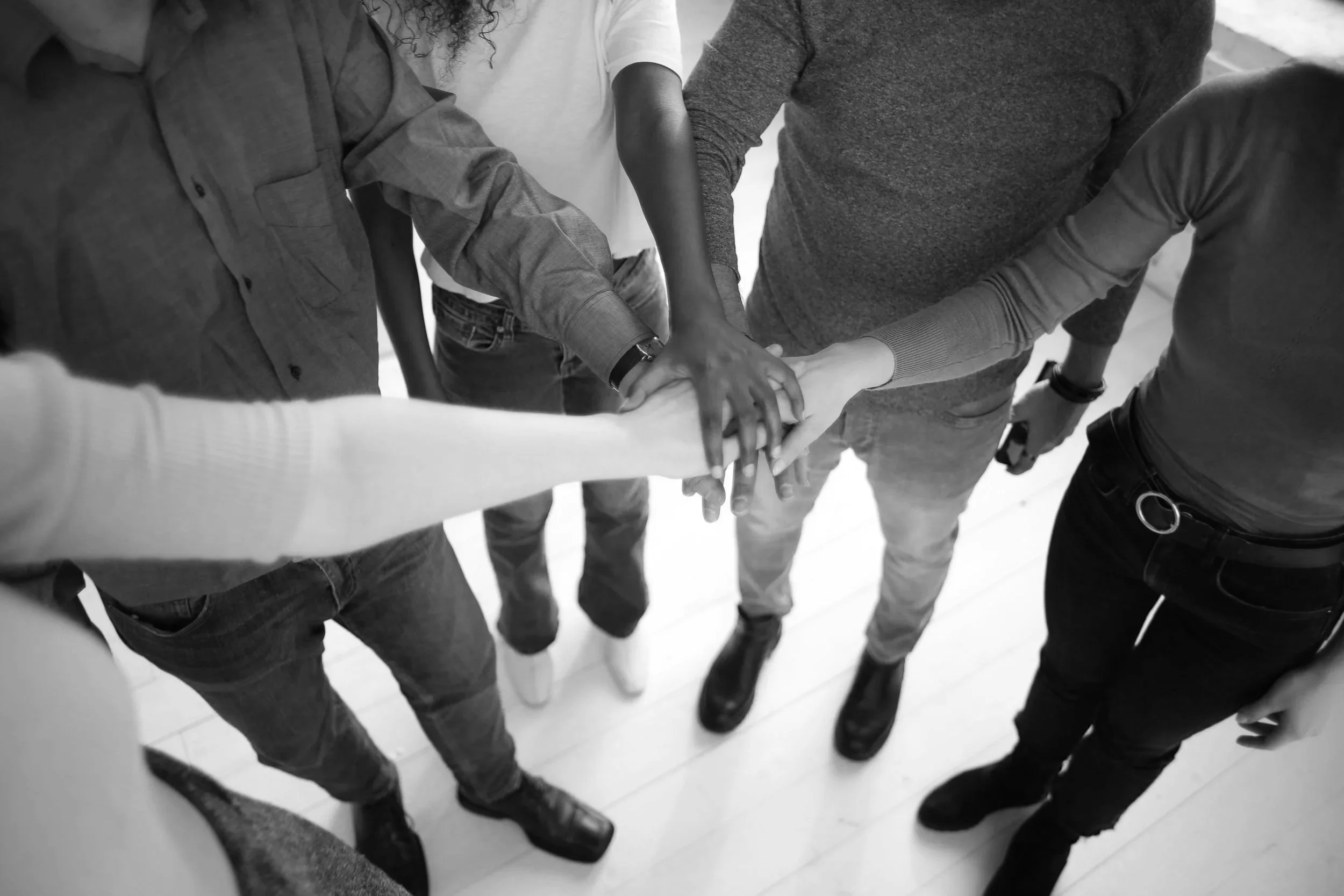 Five people extending hands and stacking them on top of each other