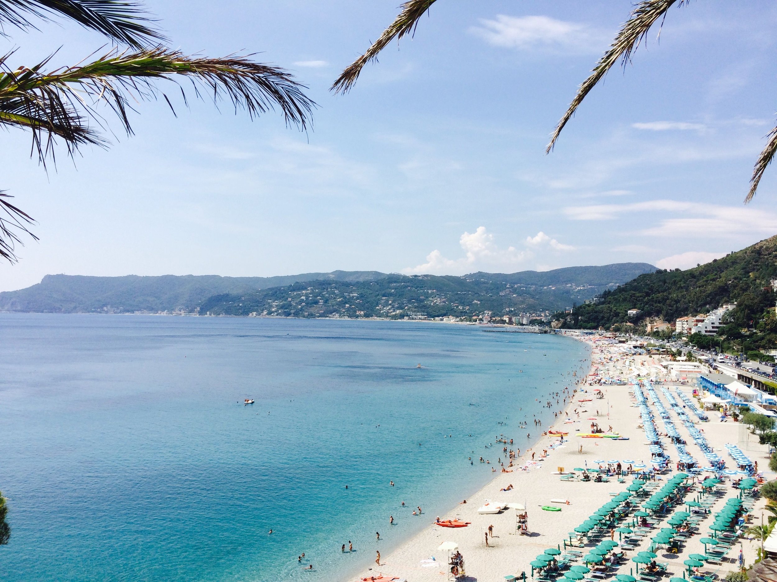 Wide sandy beach and turquoise sea along the Ligurian coast, one of the best places in what to see in Liguria for a relaxing day by the water.