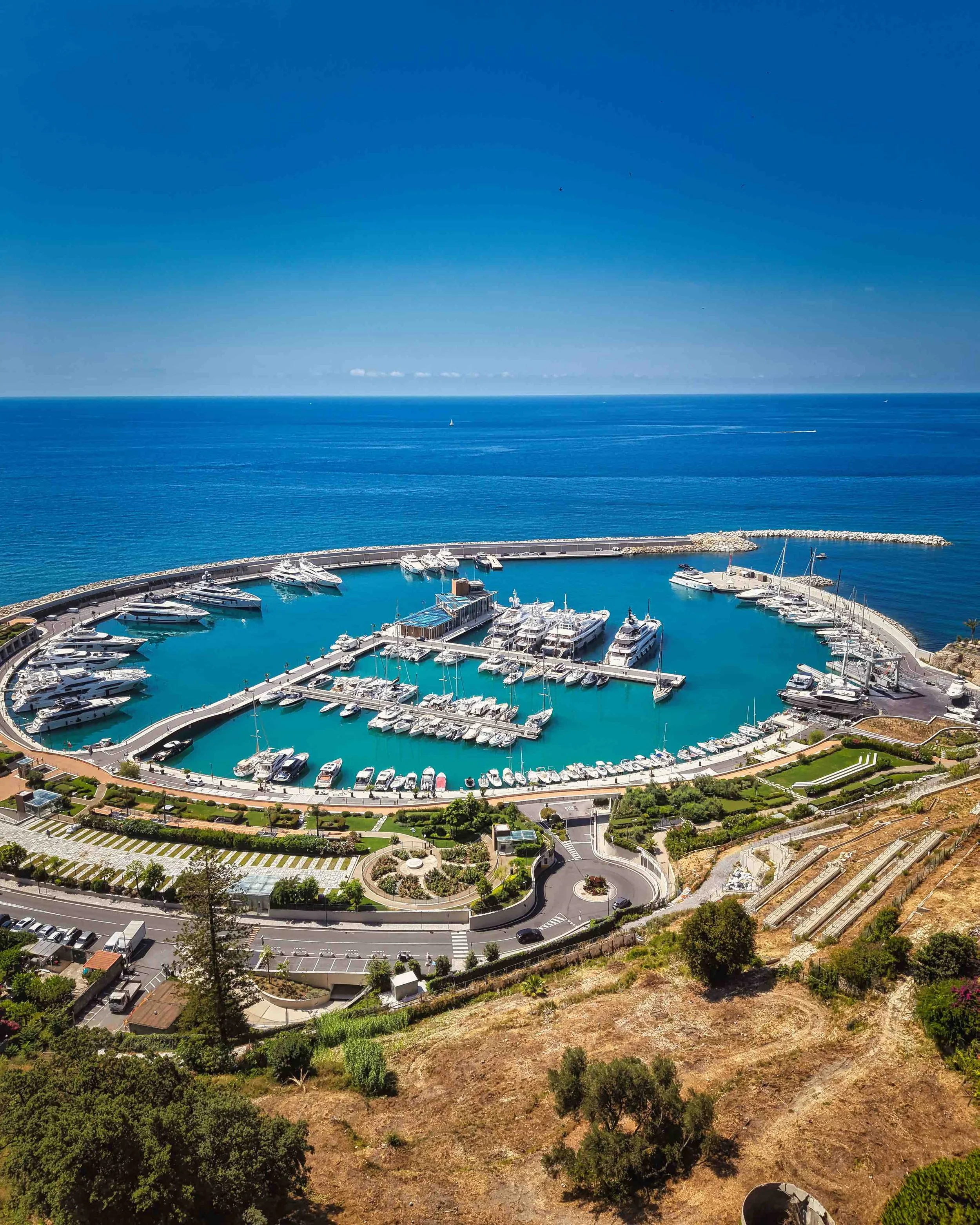Panoramic view of Porto di Ventimiglia marina on the Ligurian coast, with luxury yachts, turquoise Mediterranean waters and the Italian Riviera.