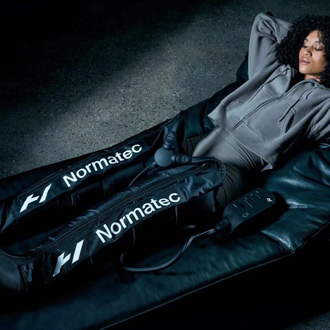 A woman lying on a black sofa with her legs in a black compression bag