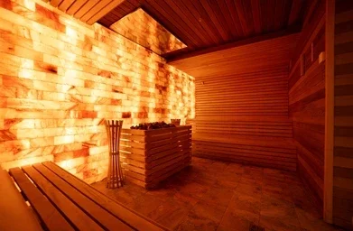 Sauna room with wooden benches, a brick wall, and warm lighting.