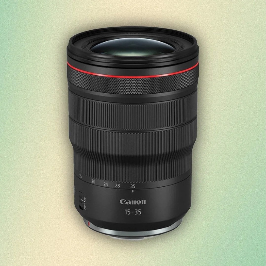 A person holding a camera with a large lens, with a blue background.