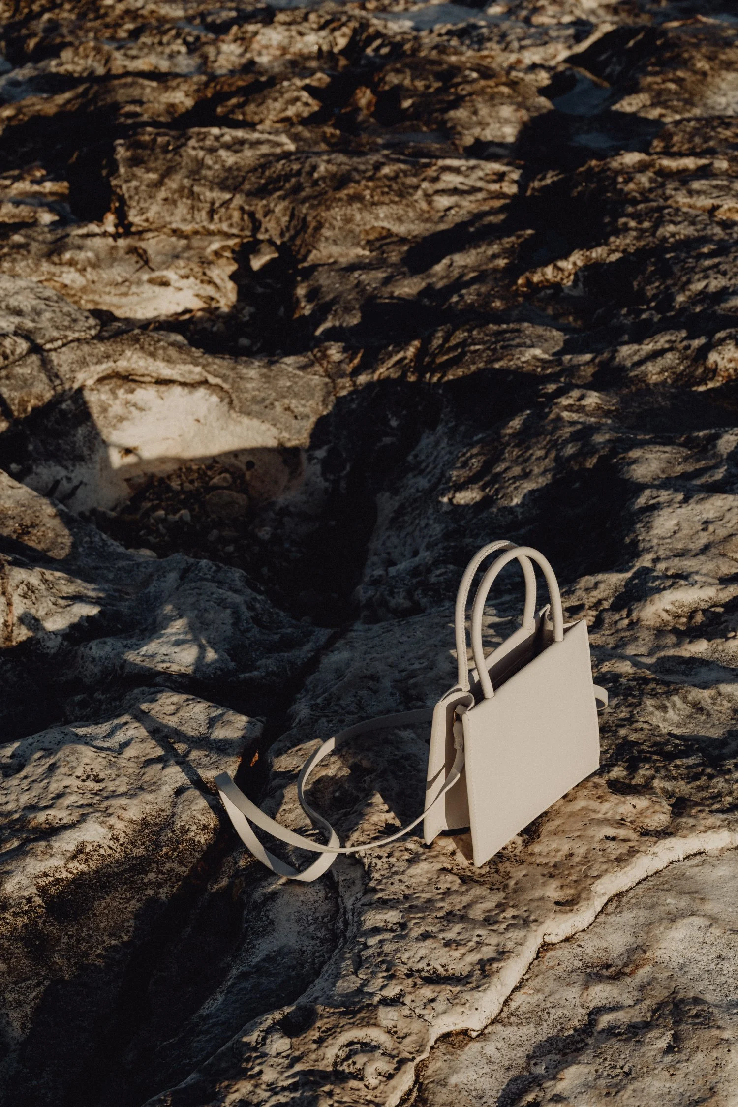 Premium Squarespace Template, Coaching Squarespace Template, Avelã Creative. Beige handbag on rocky ground in sunlight.