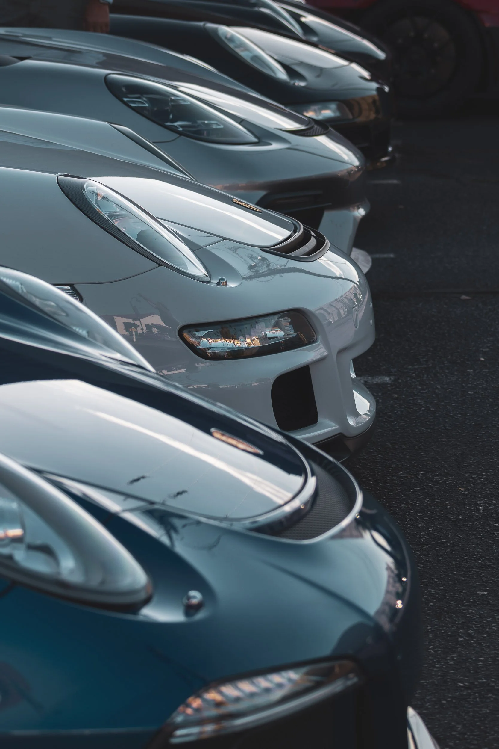 Exotic car photography showcasing a tightly parked lineup of exotic Porsche models, focusing on the aerodynamic hood vents and headlights in Scottsdale, Arizona, photographed by Curtis from Gasoline and Dopamine.