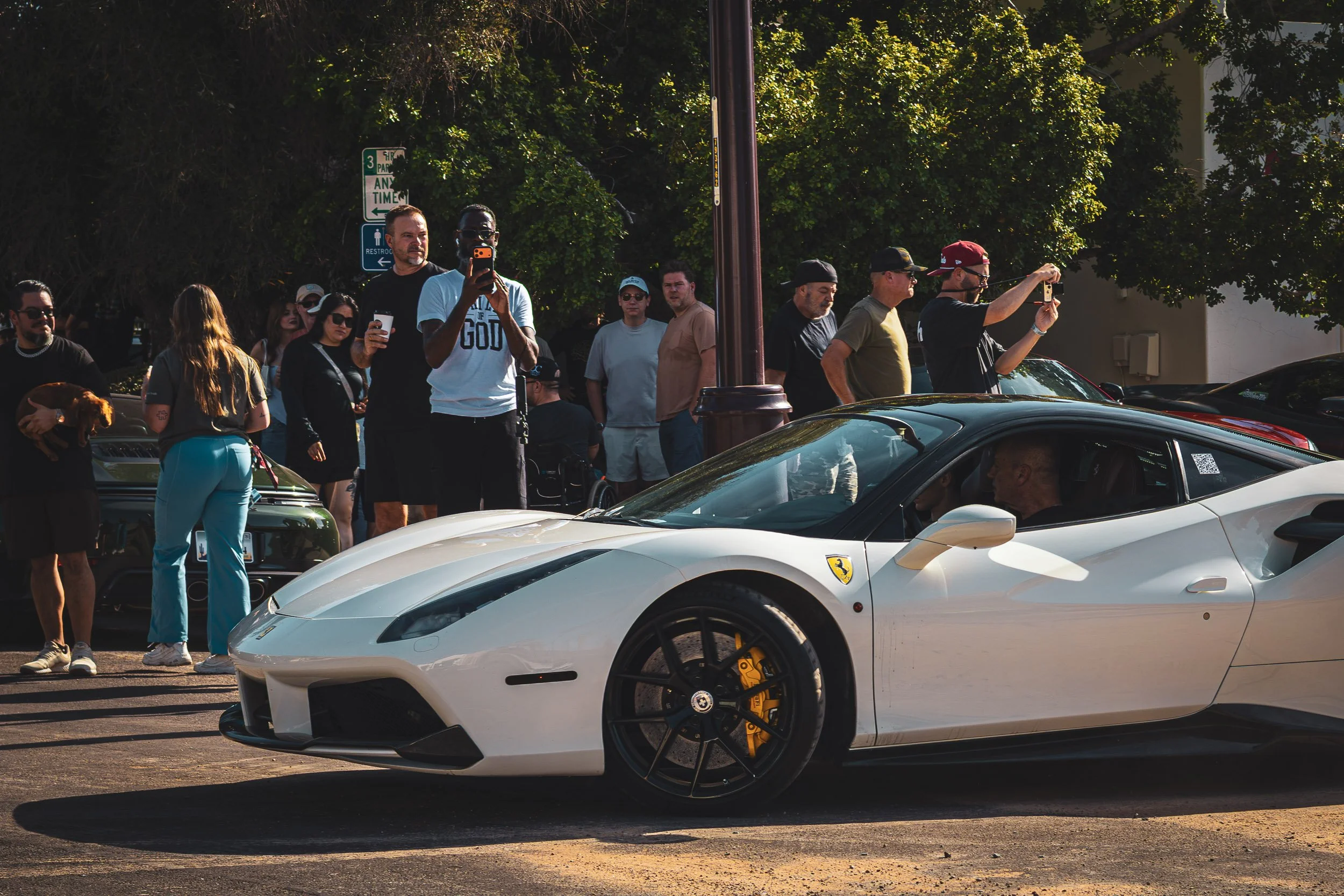 A candid slice of Arizona car culture featuring enthusiasts gathered around a sleek white Ferrari, captured at a morning event by Gasoline and Dopamine.