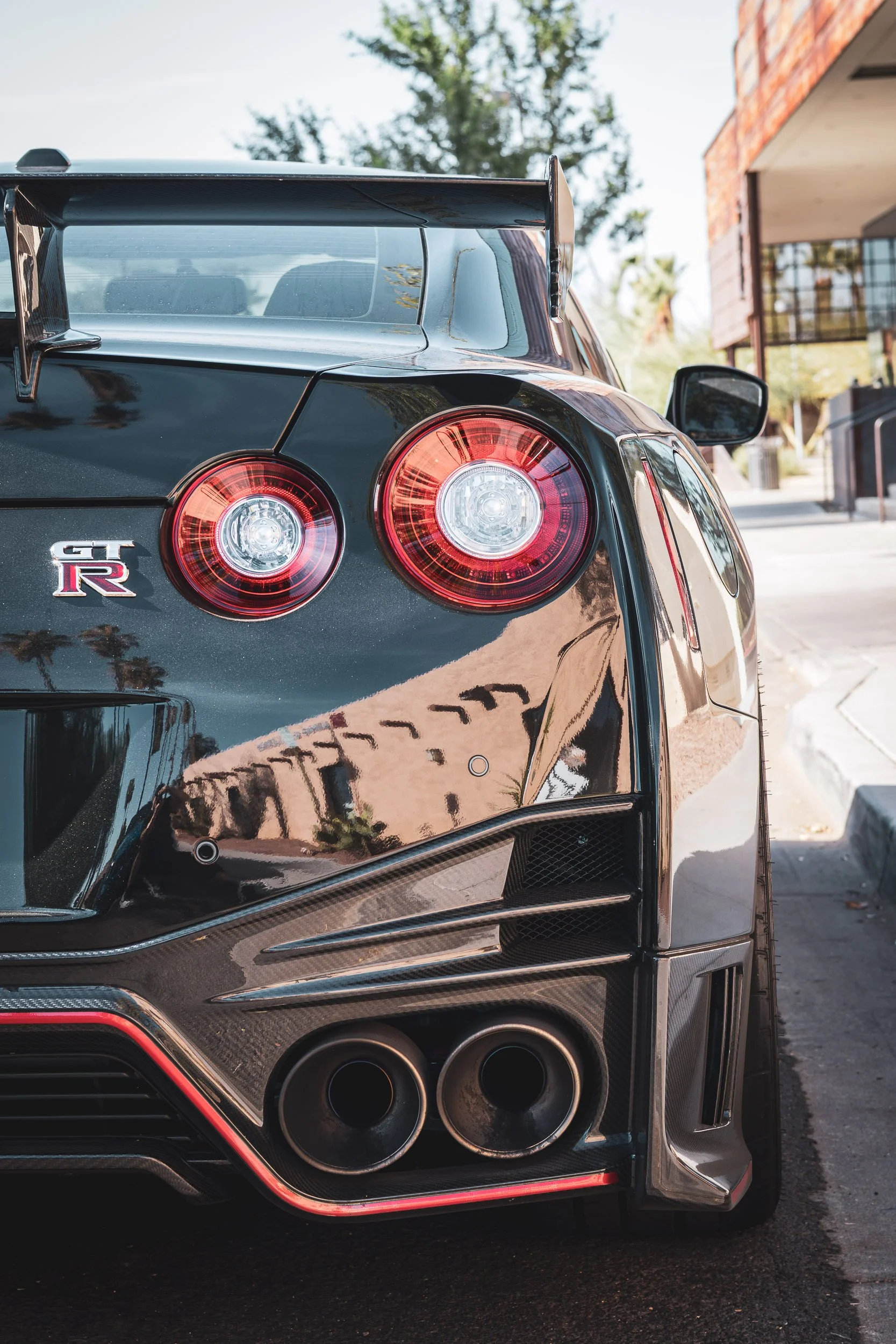 Detail car photography focusing on the iconic round taillights, carbon fiber rear diffuser, and massive exhaust tips of a black Nissan GT-R in Scottsdale, Arizona, captured by Curtis from Gasoline and Dopamine.