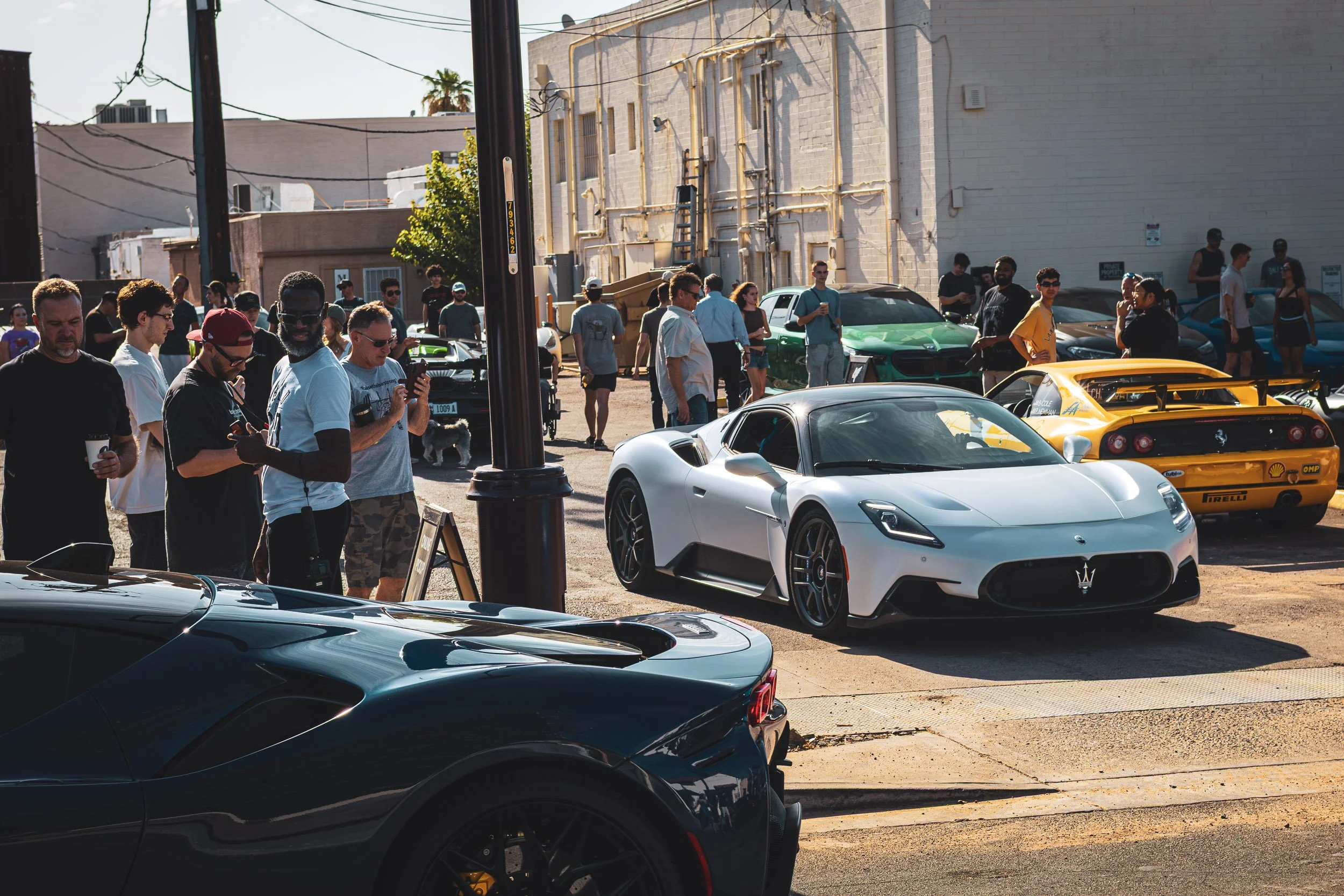 Candid automotive culture and crowd surrounding exotic supercars during a cars and coffee event at Fourtillfour in Scottsdale, Arizona, shot by Gasoline and Dopamine Automotive Photography.