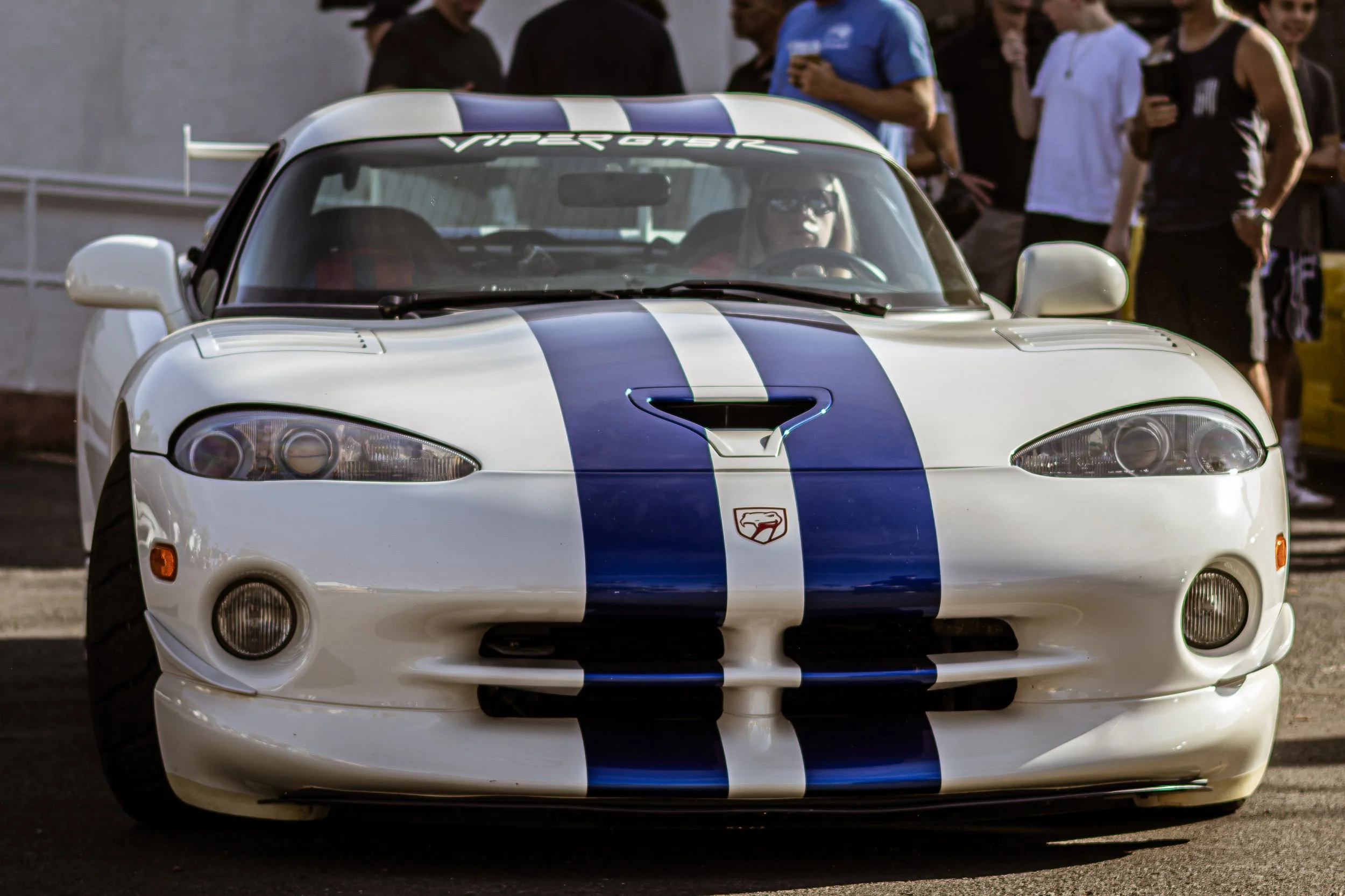Low-angle front automotive photography highlighting the aggressive crosshair grille, hood scoop, and dual blue racing stripes of a white Dodge Viper GTS-R at an Arizona car event in Scottsdale, shot by Gasoline and Dopamine.