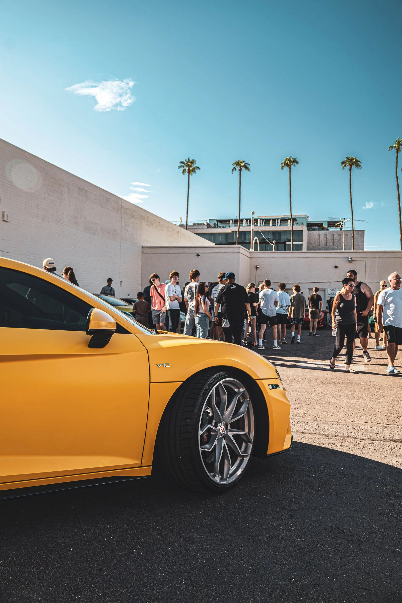 Candid automotive photography of a crowd gathering near a yellow Audi R8 V10 at a Phoenix East Valley car meet, captured by Gasoline and Dopamine Car Photography.
