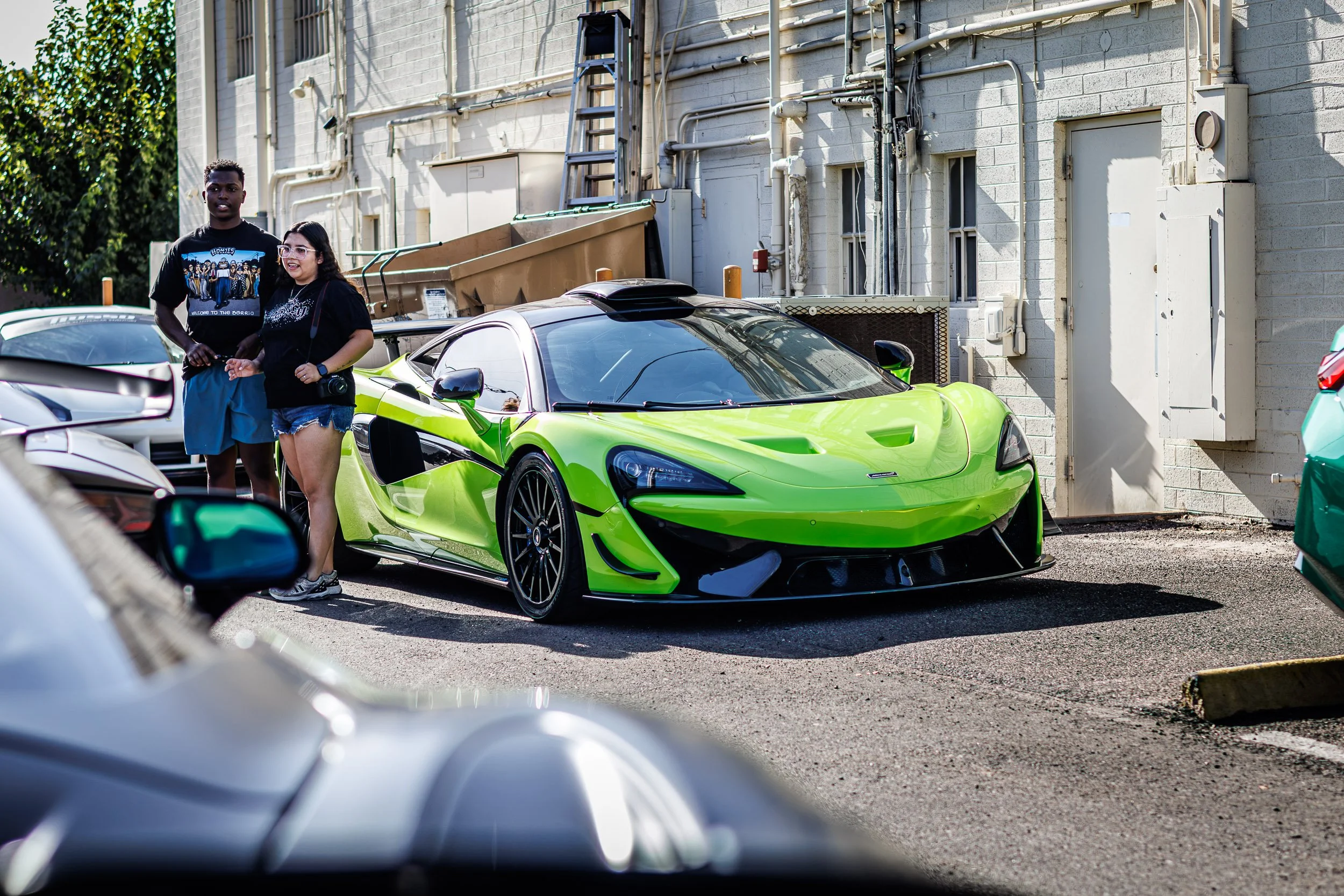 Candid car photography of a couple admiring a custom neon green McLaren with a roof scoop in Scottsdale, Arizona captured by Curtis from Gasoline and Dopamine LLC.