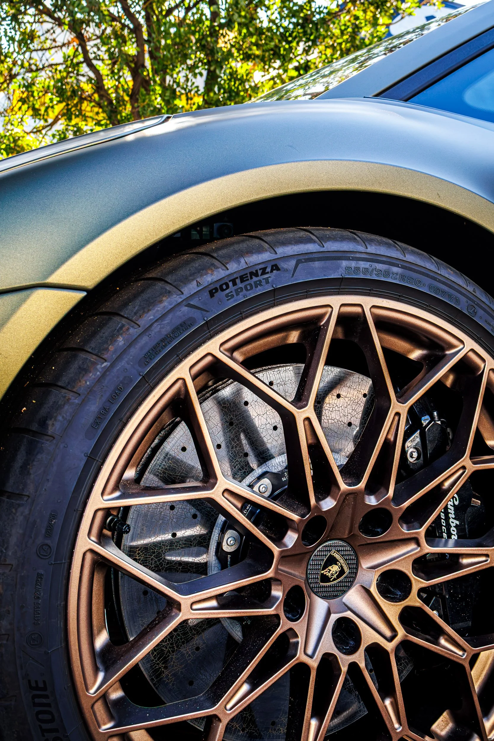 Macro automotive detail photography focusing on the intricate bronze multi-spoke wheel, massive carbon-ceramic brakes, and iconic Lamborghini center cap of a satin green Lamborghini Temerario in Gilbert, Arizona, shot by Curtis at Gasoline and Dopami