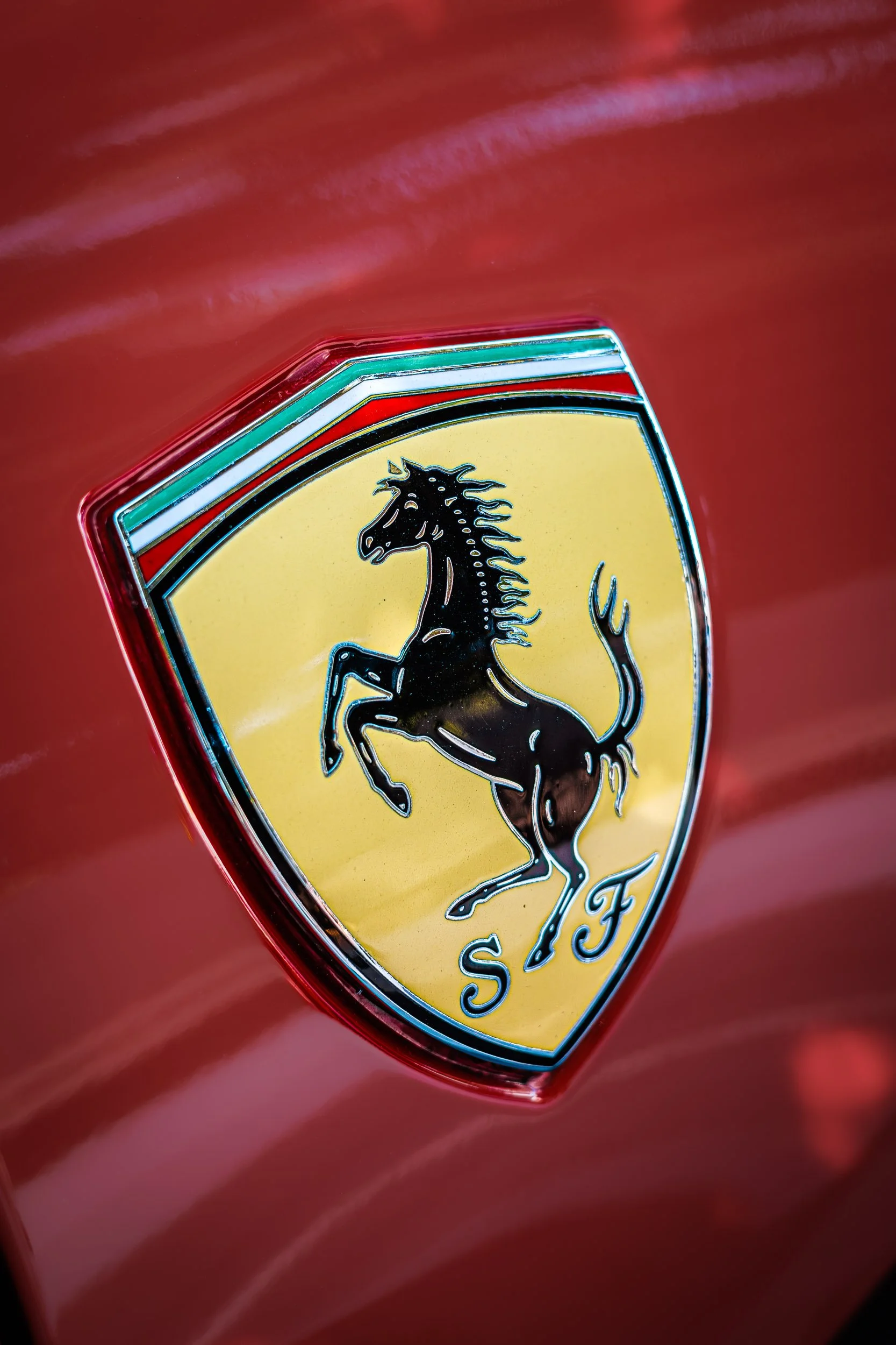 Macro detail exotic car photography highlighting the iconic yellow Scuderia Ferrari prancing horse shield emblem set against vibrant red paint, captured by Curtis from Gasoline and Dopamine in Gilbert, Arizona.