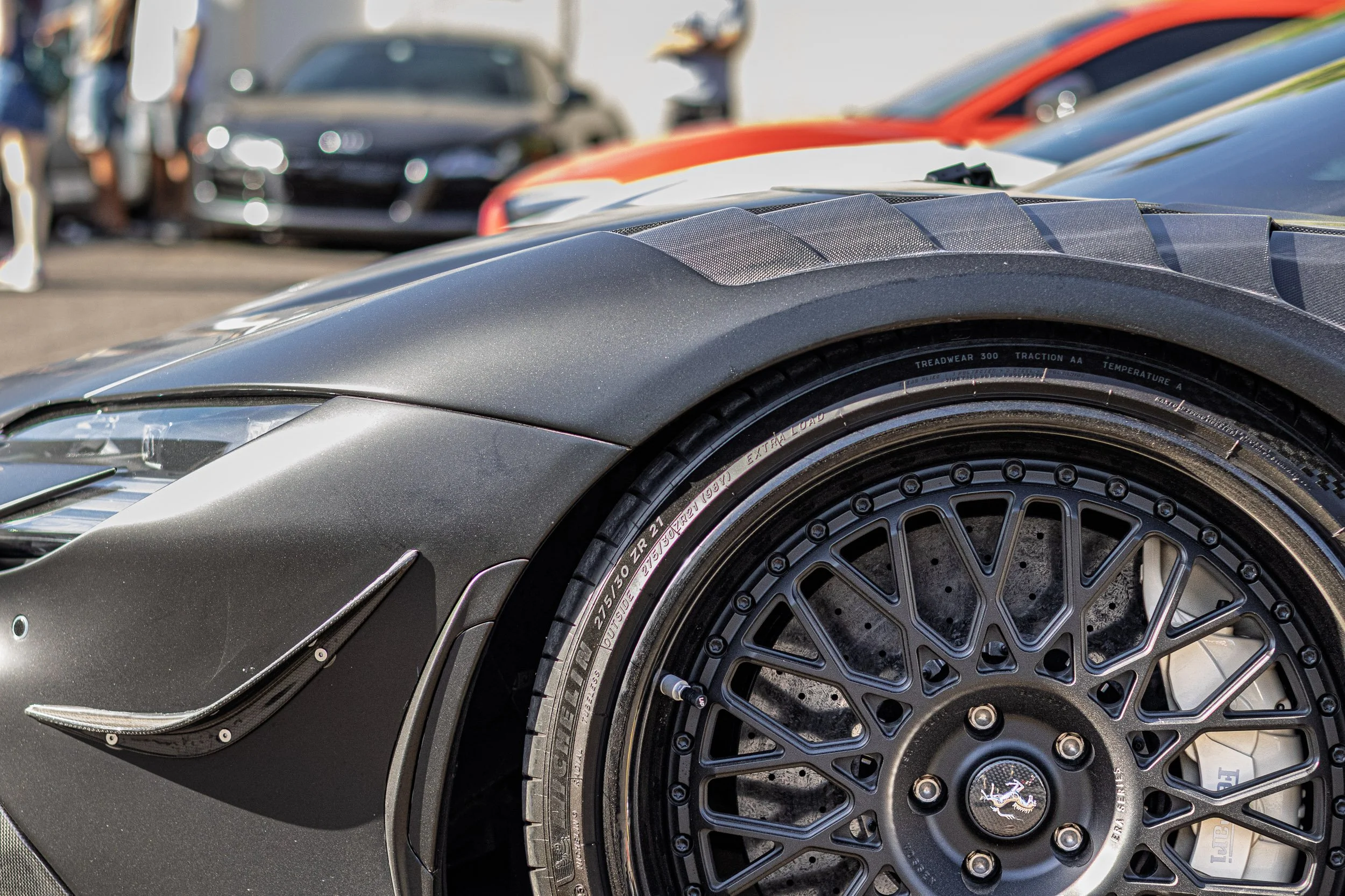 Fine-art car photography of a matte black exotic supercar in Scottsdale, AZ, featuring a macro detail shot of the custom wheel fitment and carbon fiber fender louvers shot by Gasoline and Dopamine Automotive Photography.