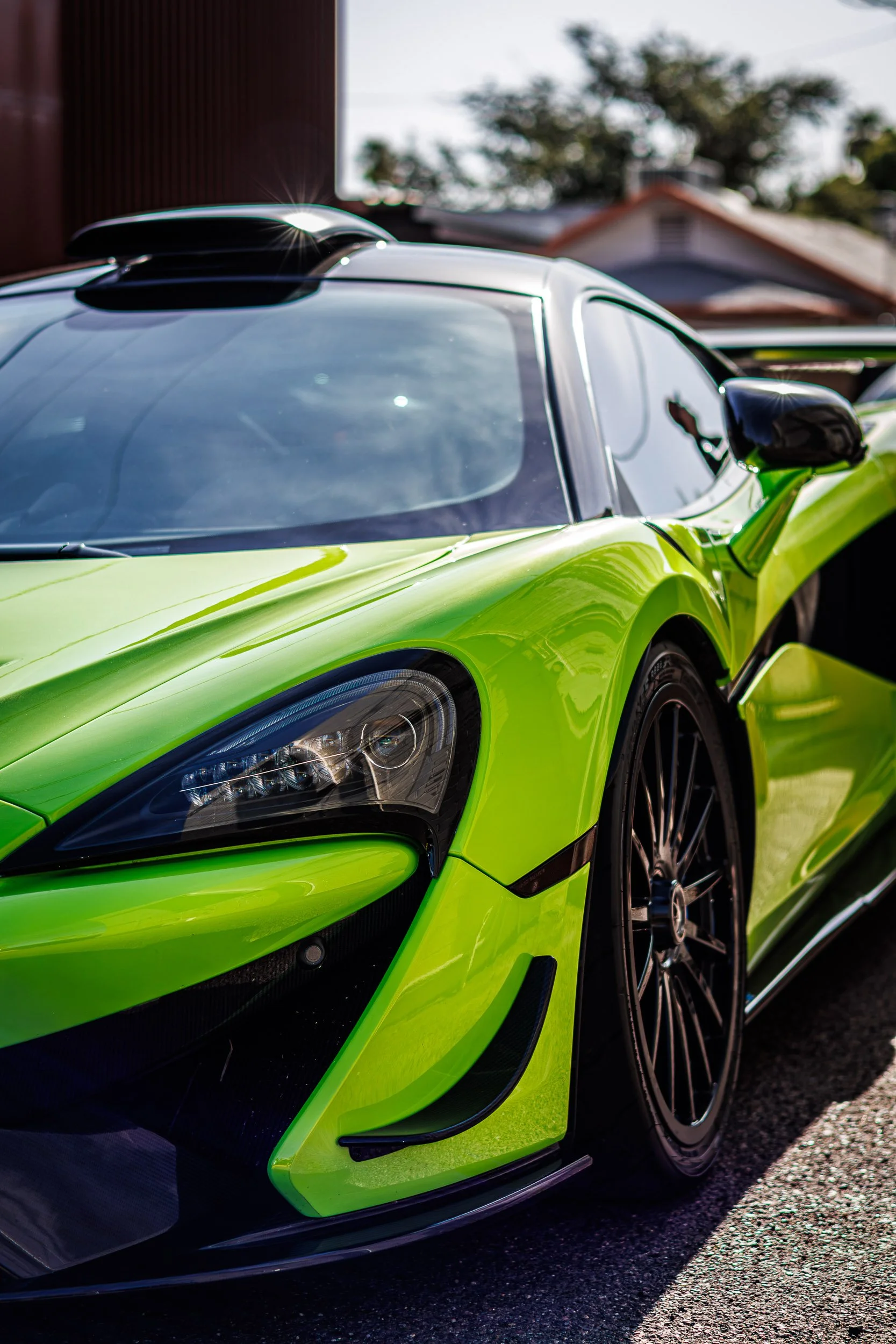 Vertical automotive photography highlighting the vibrant neon green paint, custom carbon fiber roof scoop catching a sun flare, and sleek front fascia of a McLaren 600LT on a sunny street in Scottsdale, Arizona, shot by Curtis at Gasoline and Dopamin
