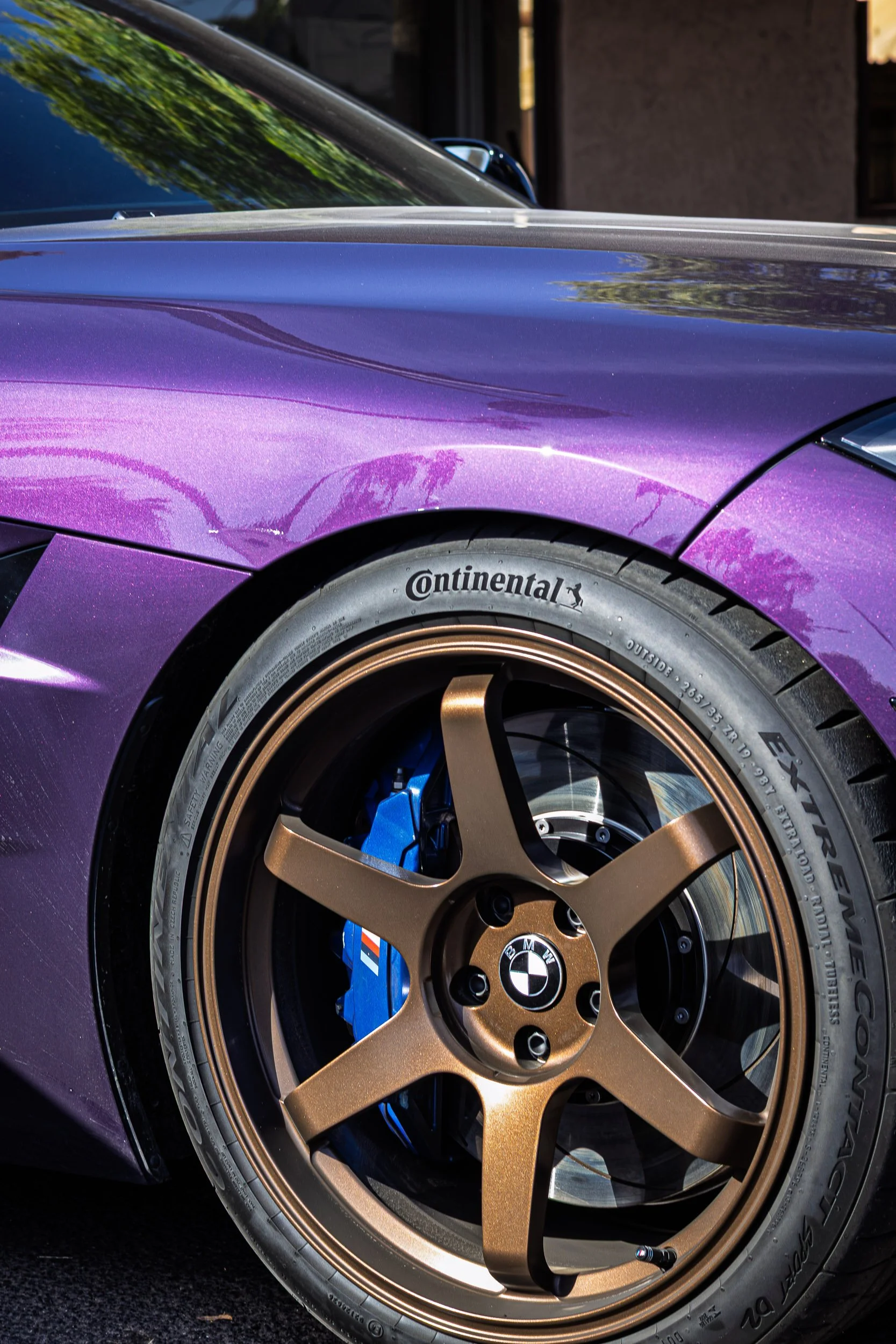 Macro detail car photography highlighting the vibrant metallic purple paint, custom bronze six-spoke wheels, and bright blue brake calipers of a BMW in Chandler, Arizona, captured by Curtis from Gasoline and Dopamine.